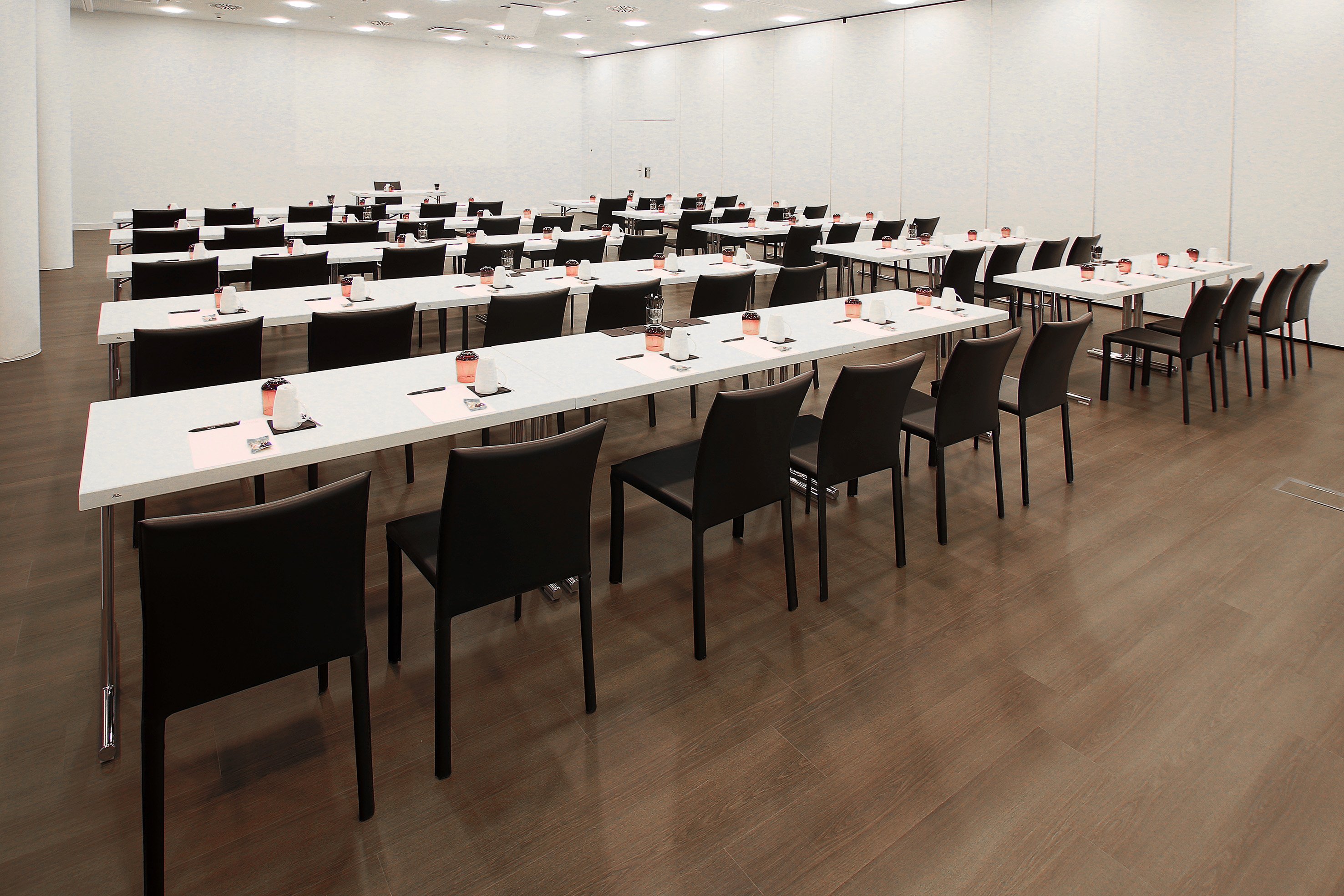 Modern conference room in classroom setup with white tables and black chairs. - Lamborghini & Bentley - INNSiDE Wolfsburg, Wolfsburg