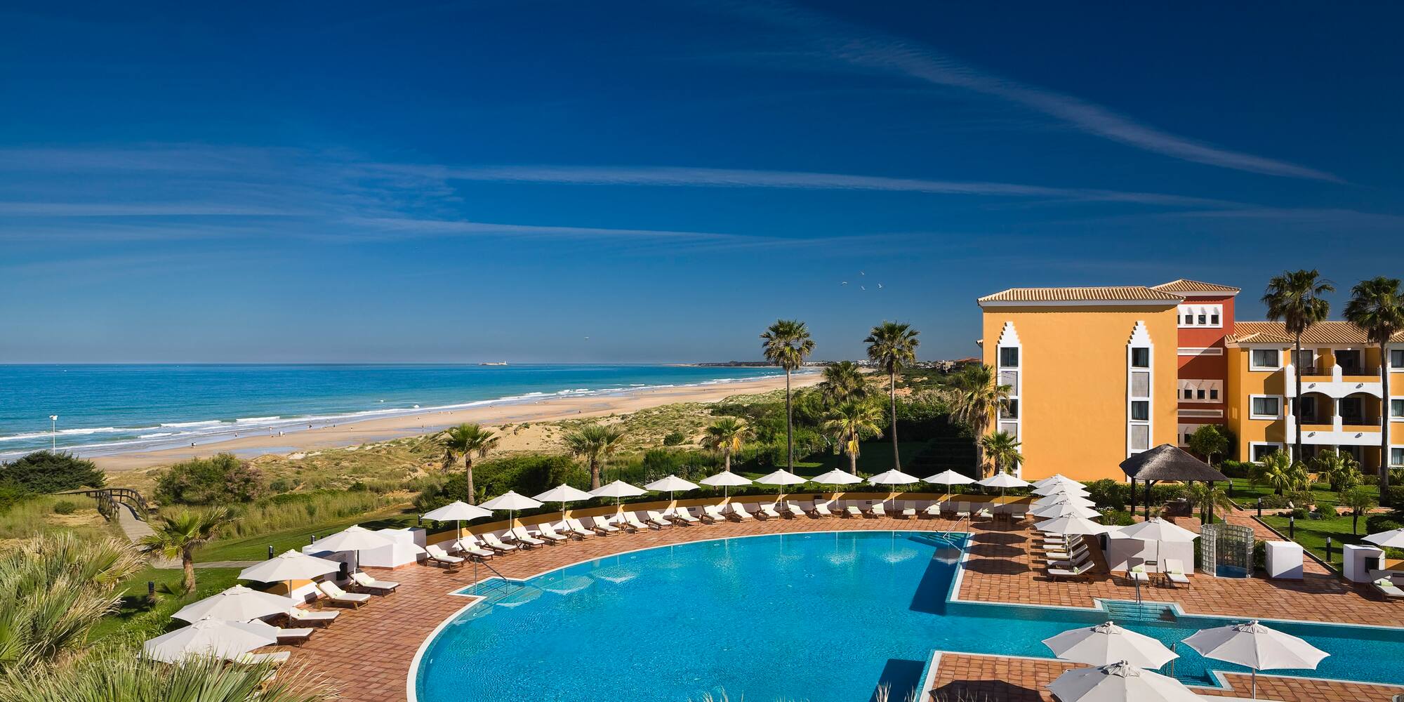 a swimming pool with umbrellas and chairs by a building