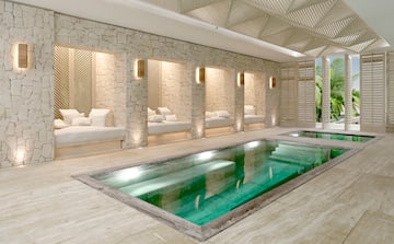 a pool with a white couches and a stone wall