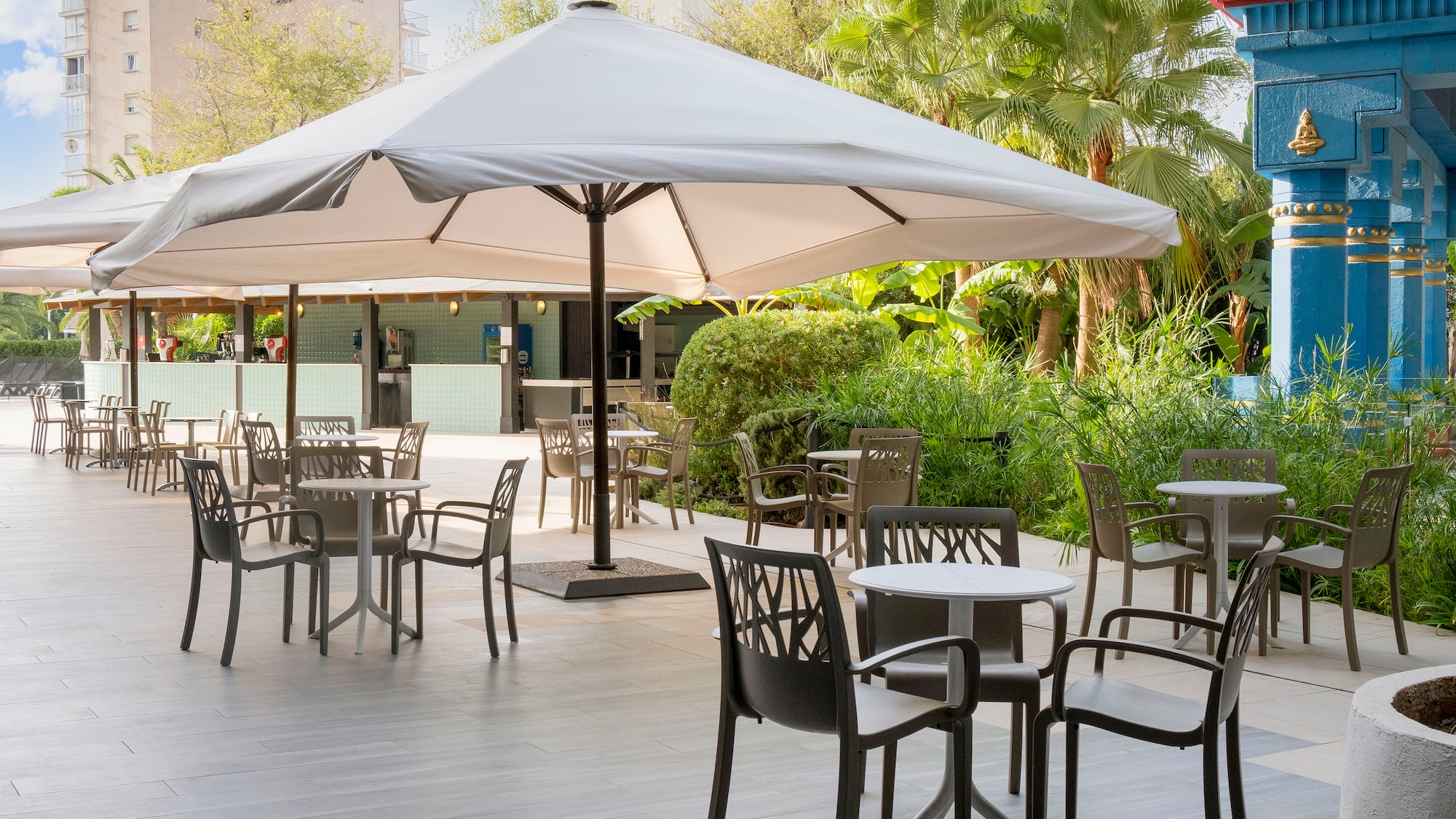 a patio with tables and chairs under a large umbrella