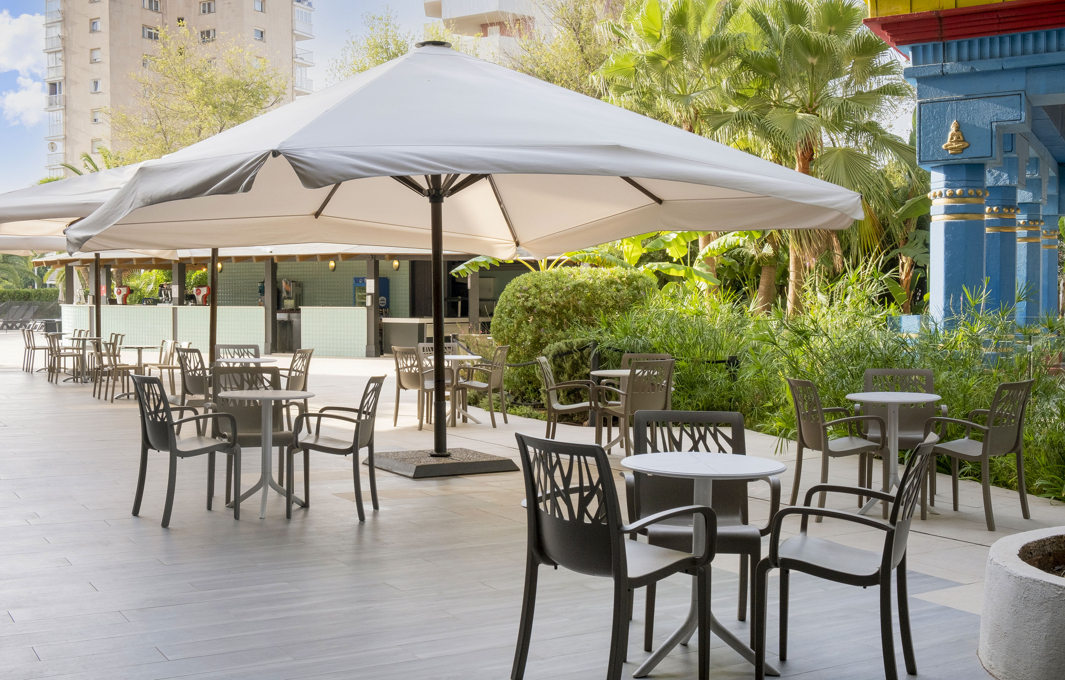 a patio with tables and chairs under a large umbrella