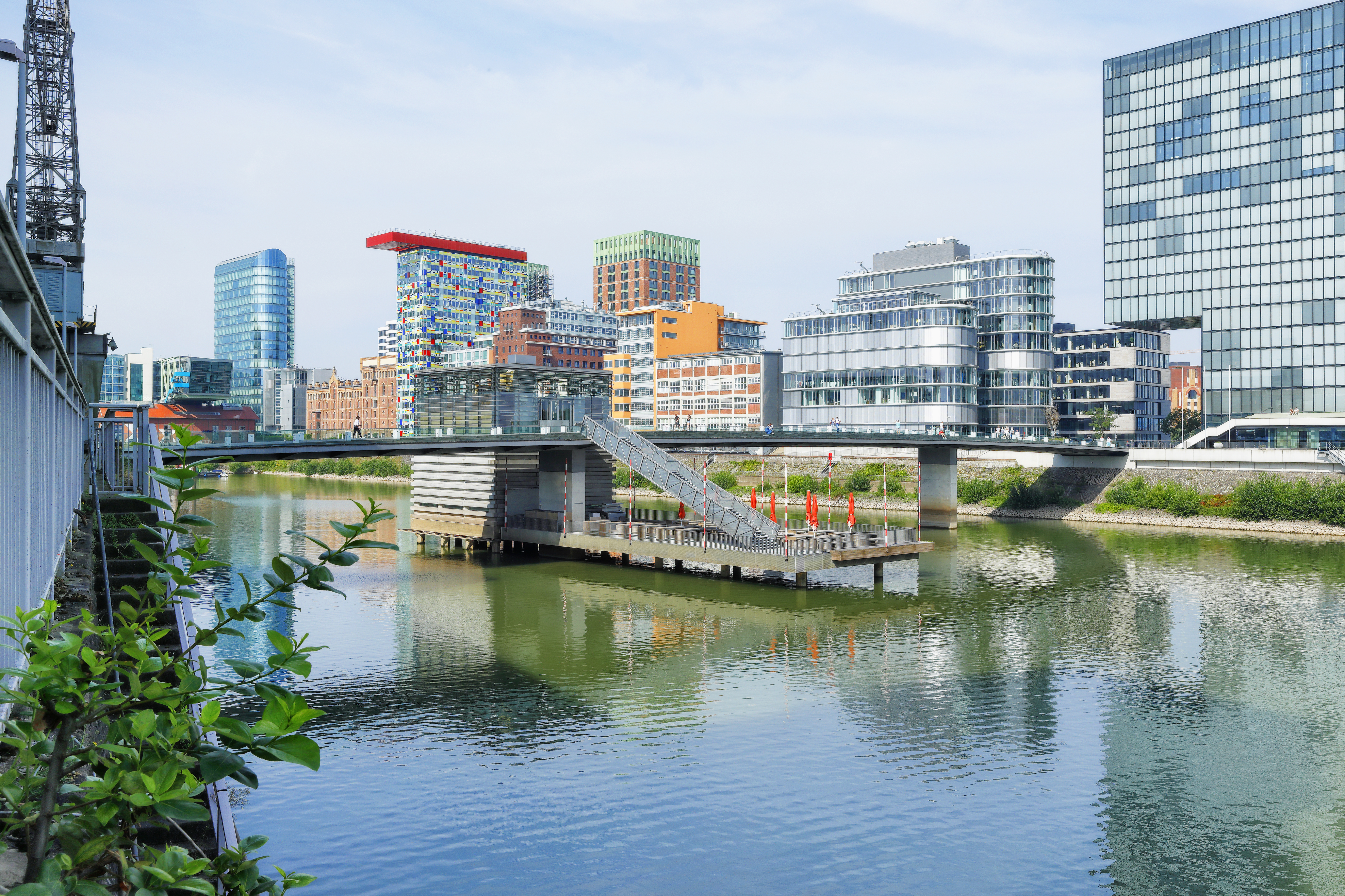 Modern Düsseldorf MedienHafen cityscape with glass buildings, bridge, and harbor.