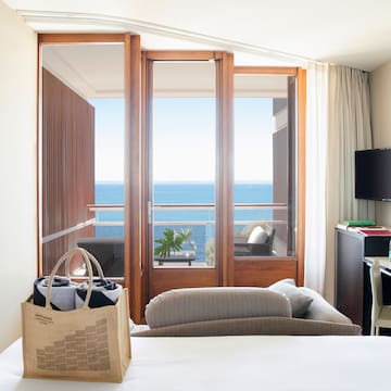 a room with a bed and a television and a beach view