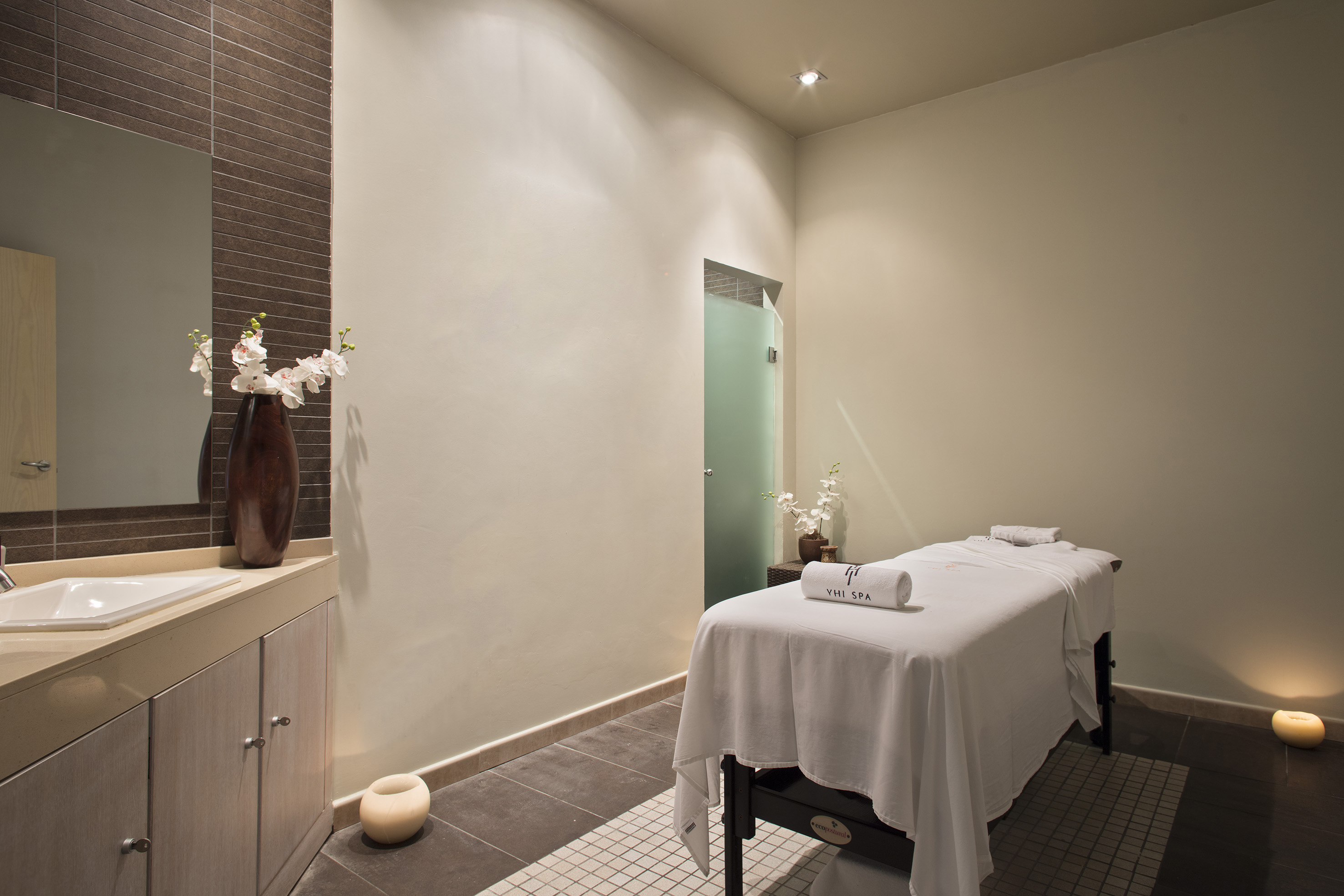 Serene YHI SPA treatment room with massage table, vanity, and orchids.
