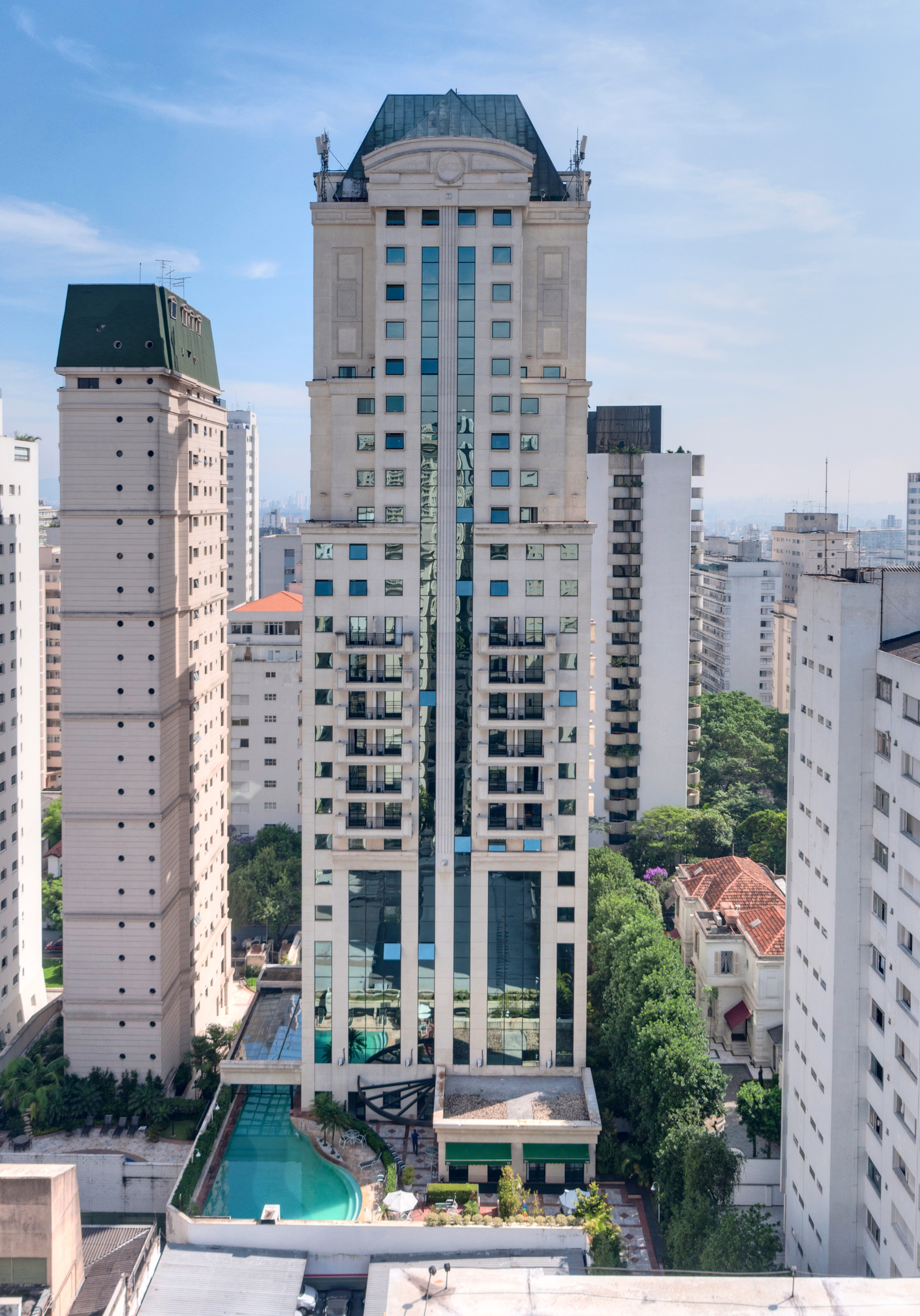 White skyscraper with green roof, reflective windows, and swimming pool.