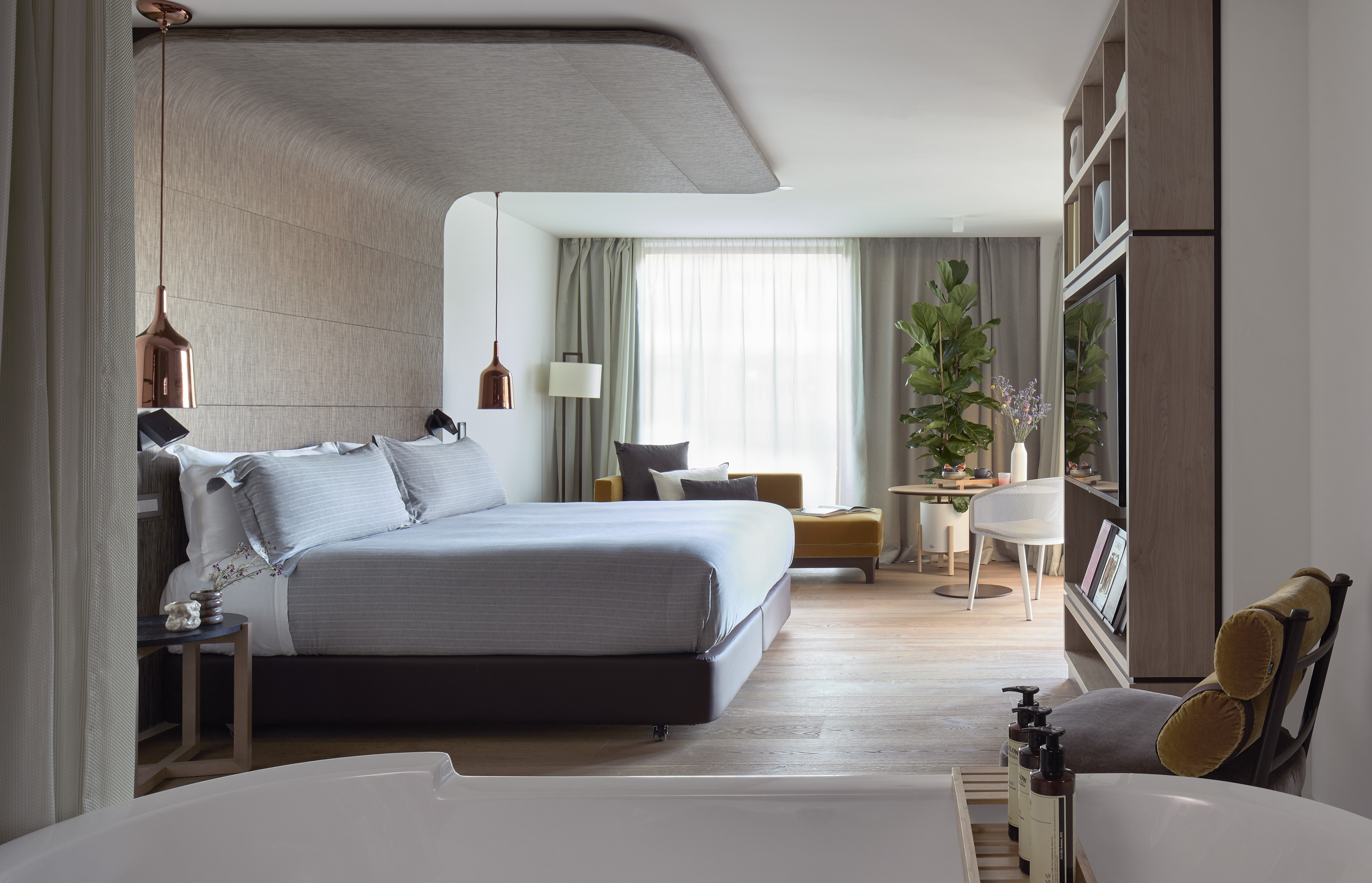 Luxury hotel room with king bed, open bathtub, and modern design.