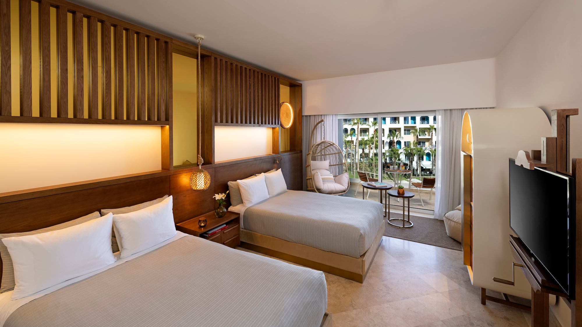 a room with two beds and a wicker chair