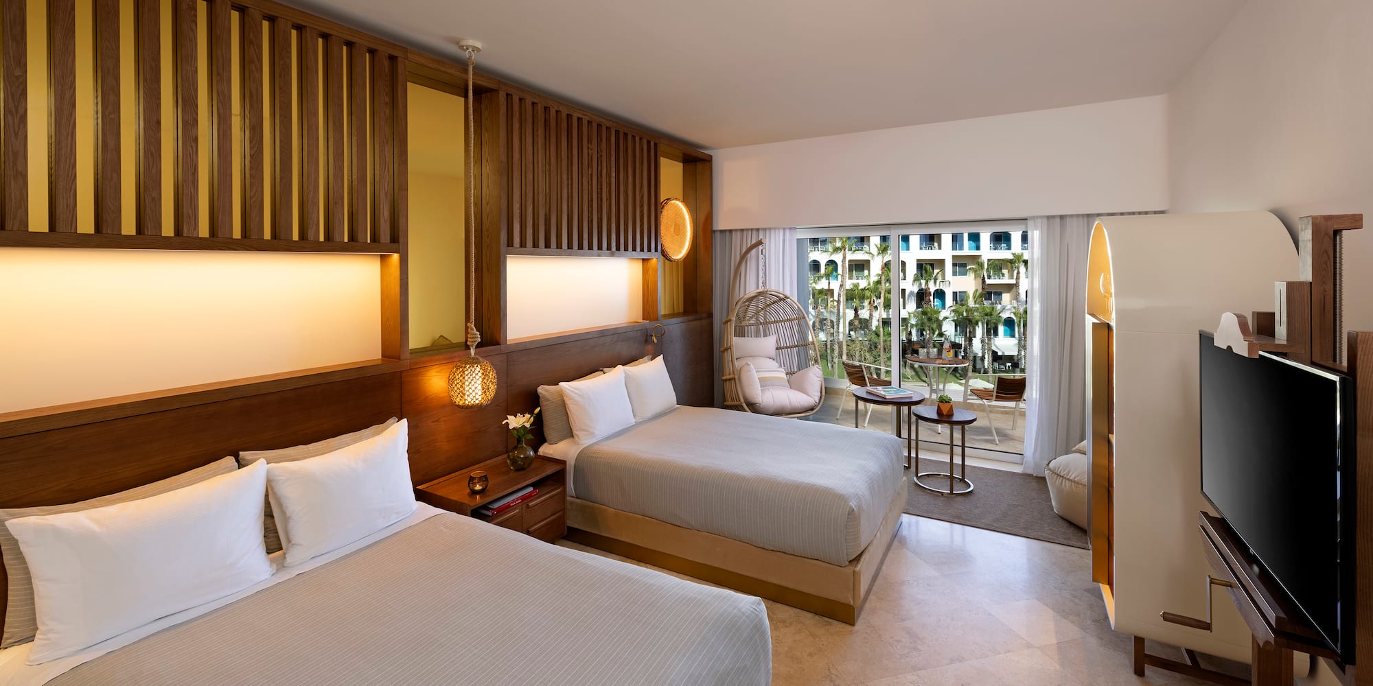 a room with two beds and a wicker chair