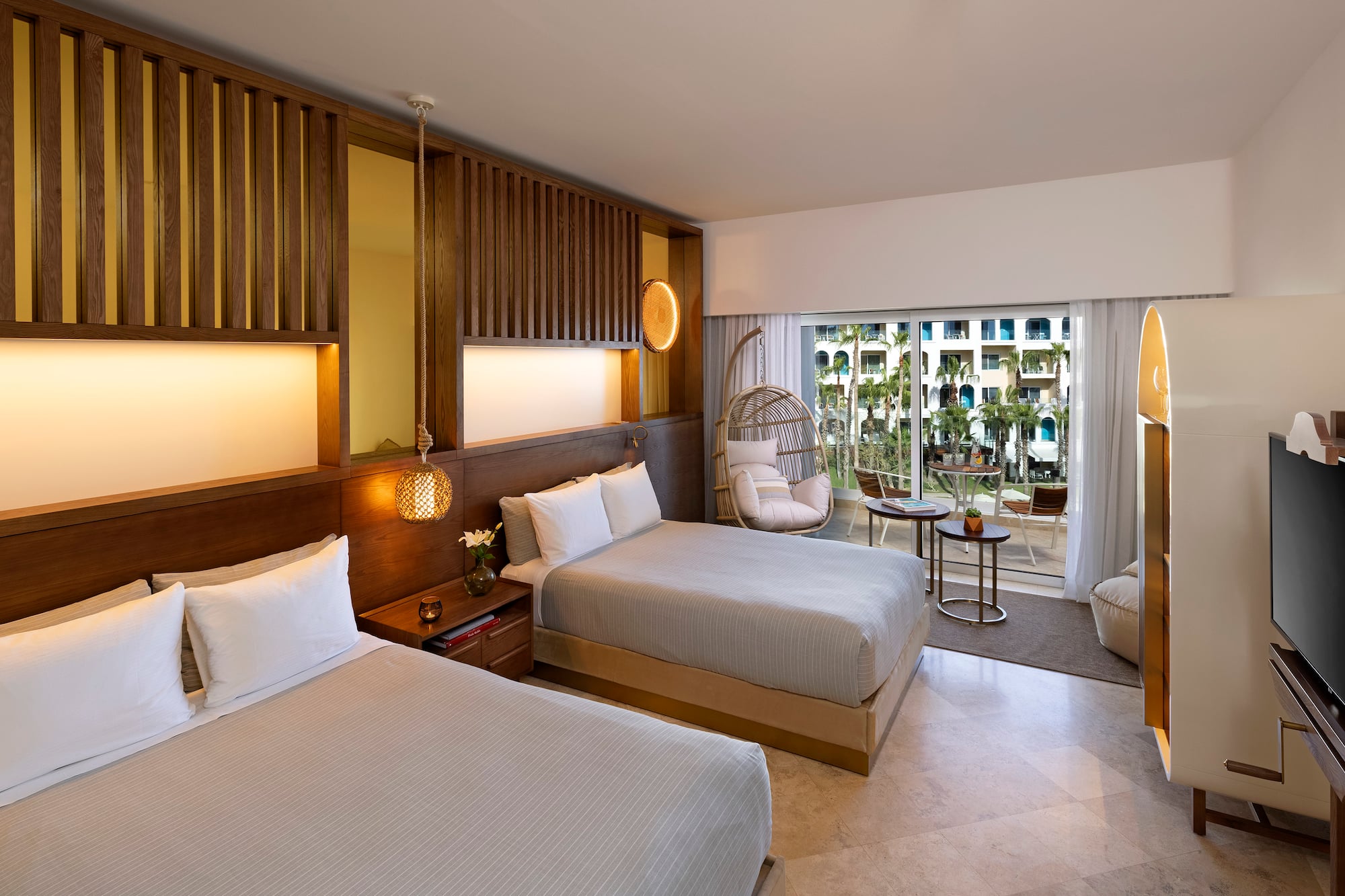 a room with two beds and a wicker chair