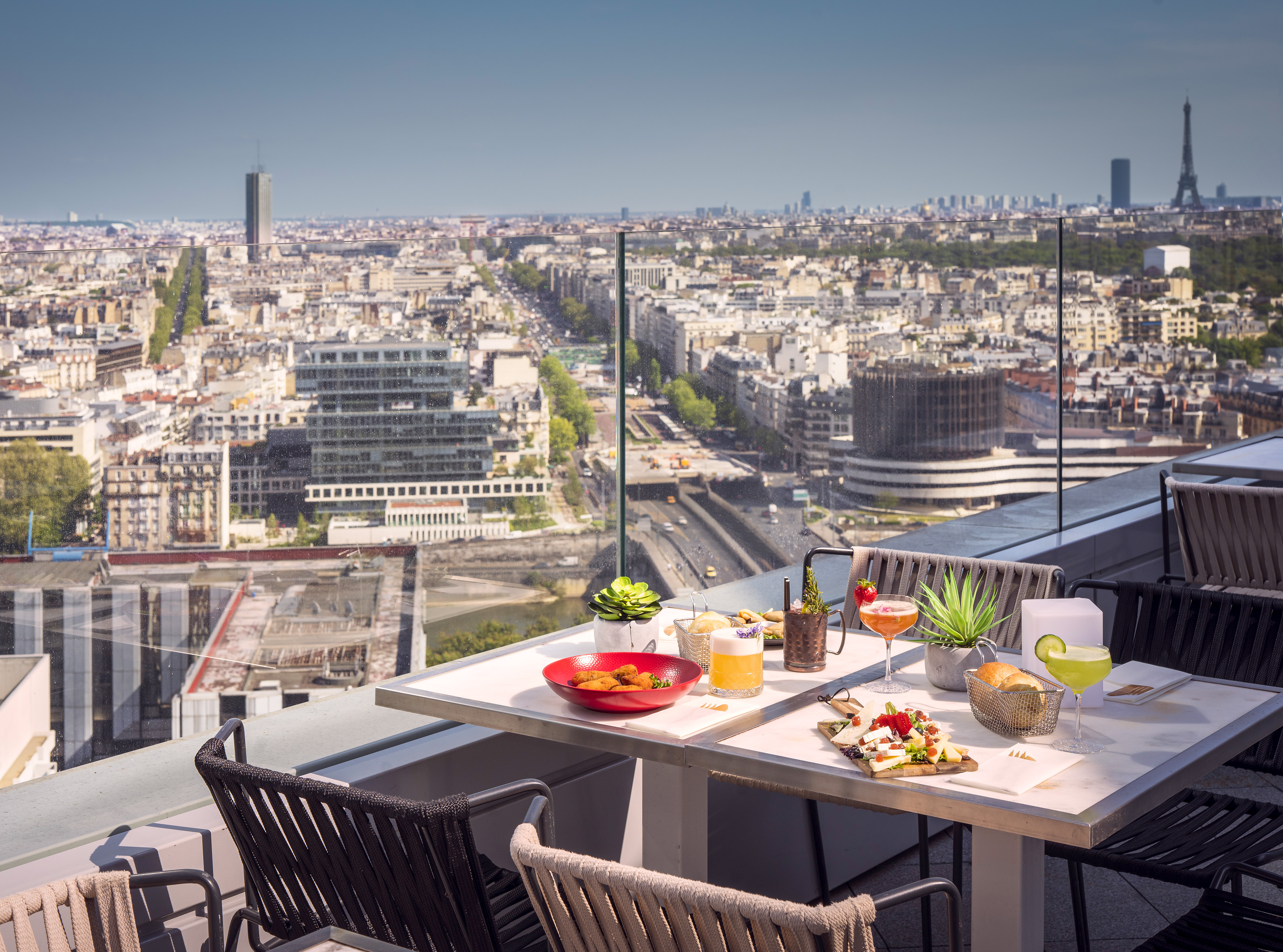 Terraza de azotea en París con comida, cócteles y vista a la Torre Eiffel.