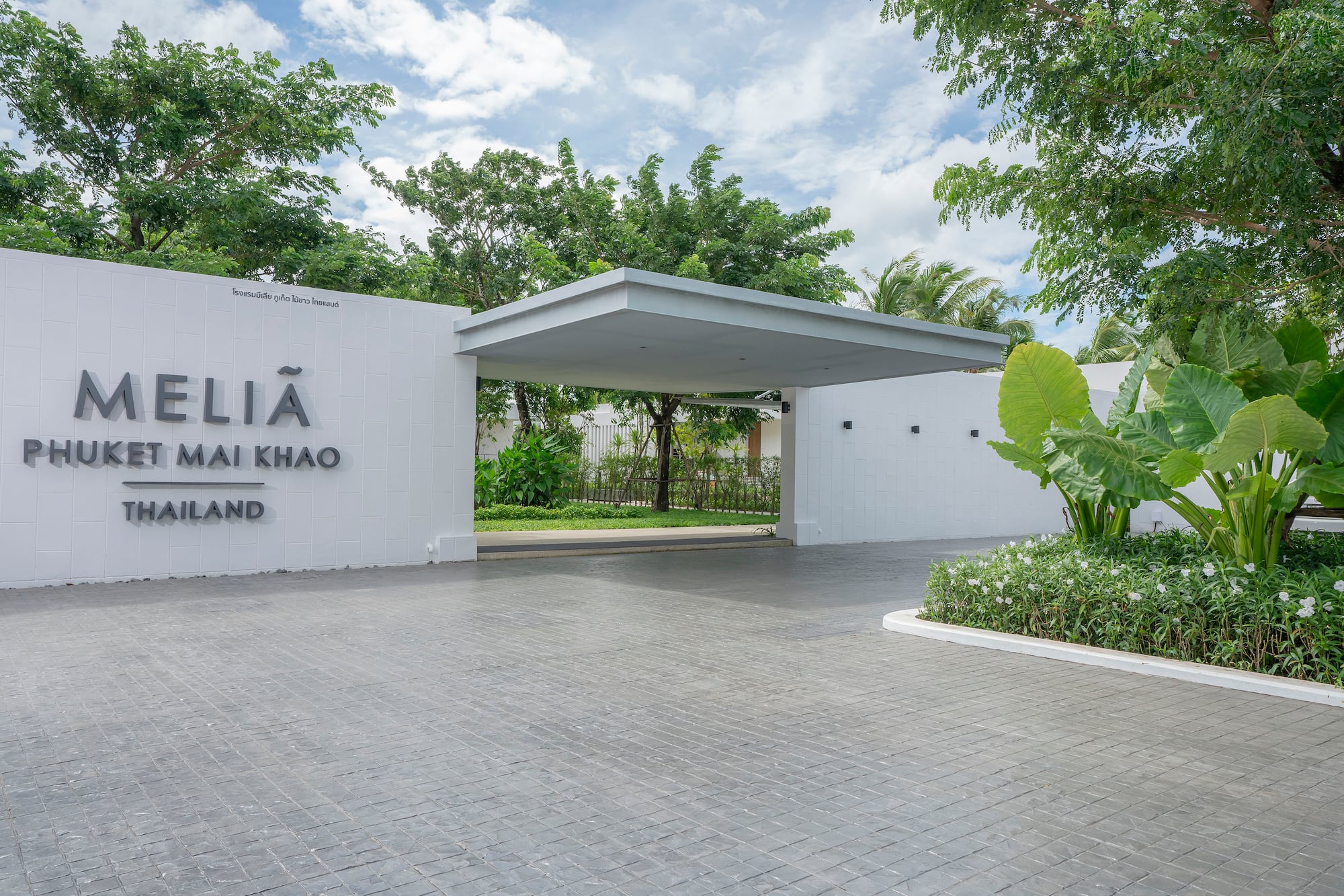 Meliá Phuket Mai Khao Thailand hotel entrance with modern architecture and lush greenery.
