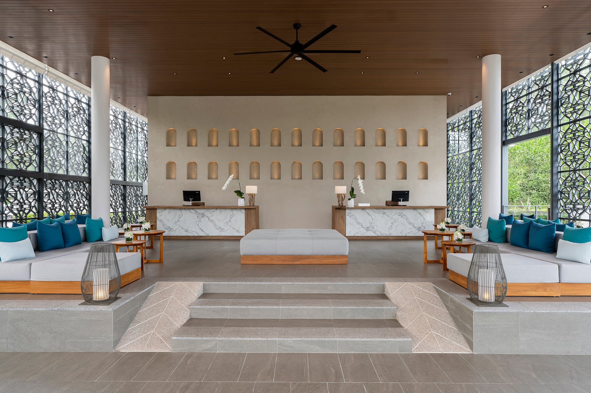 Resort lobby with twin marble reception desks, modern lounge seating.