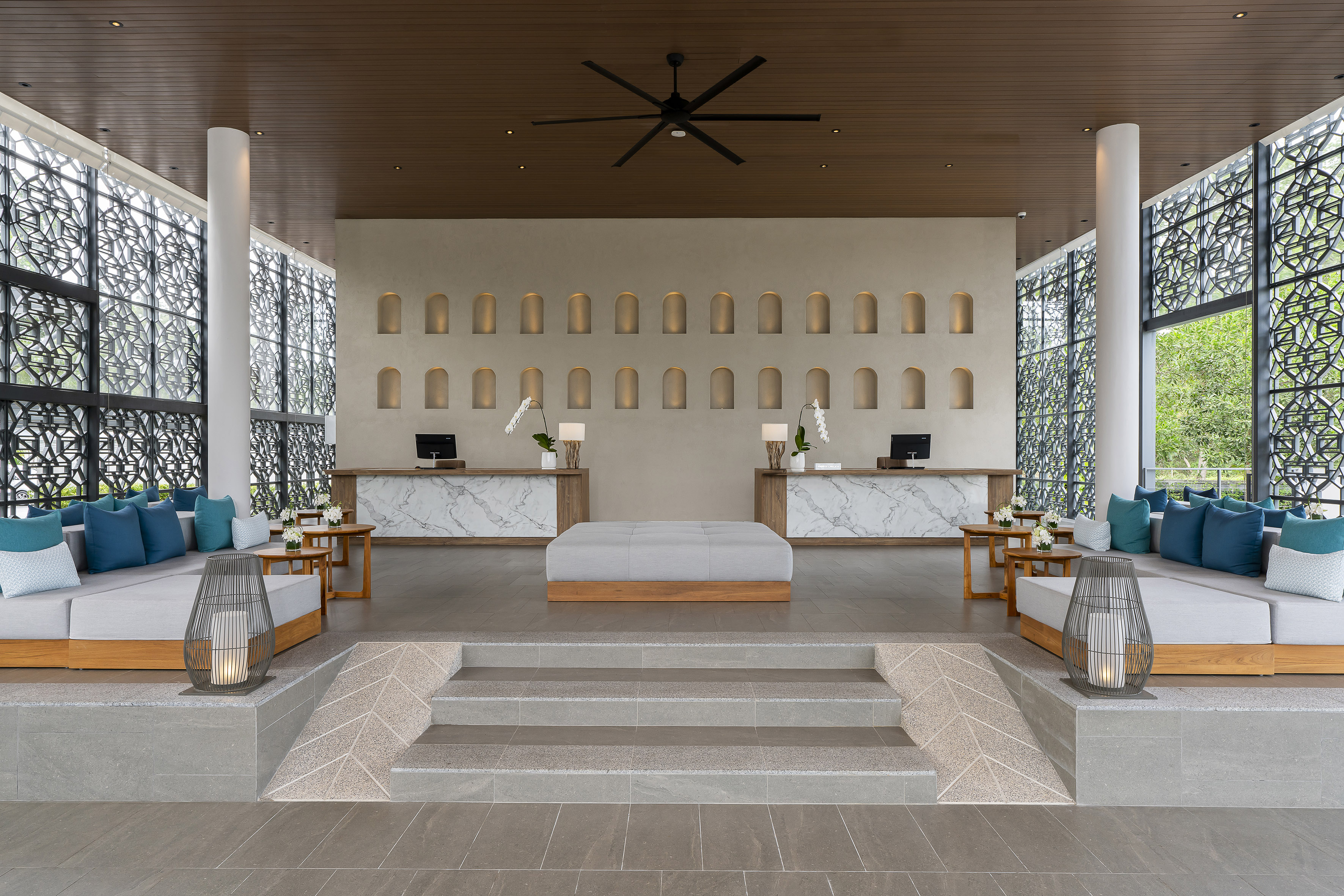 Resort lobby with twin marble reception desks, modern lounge seating.
