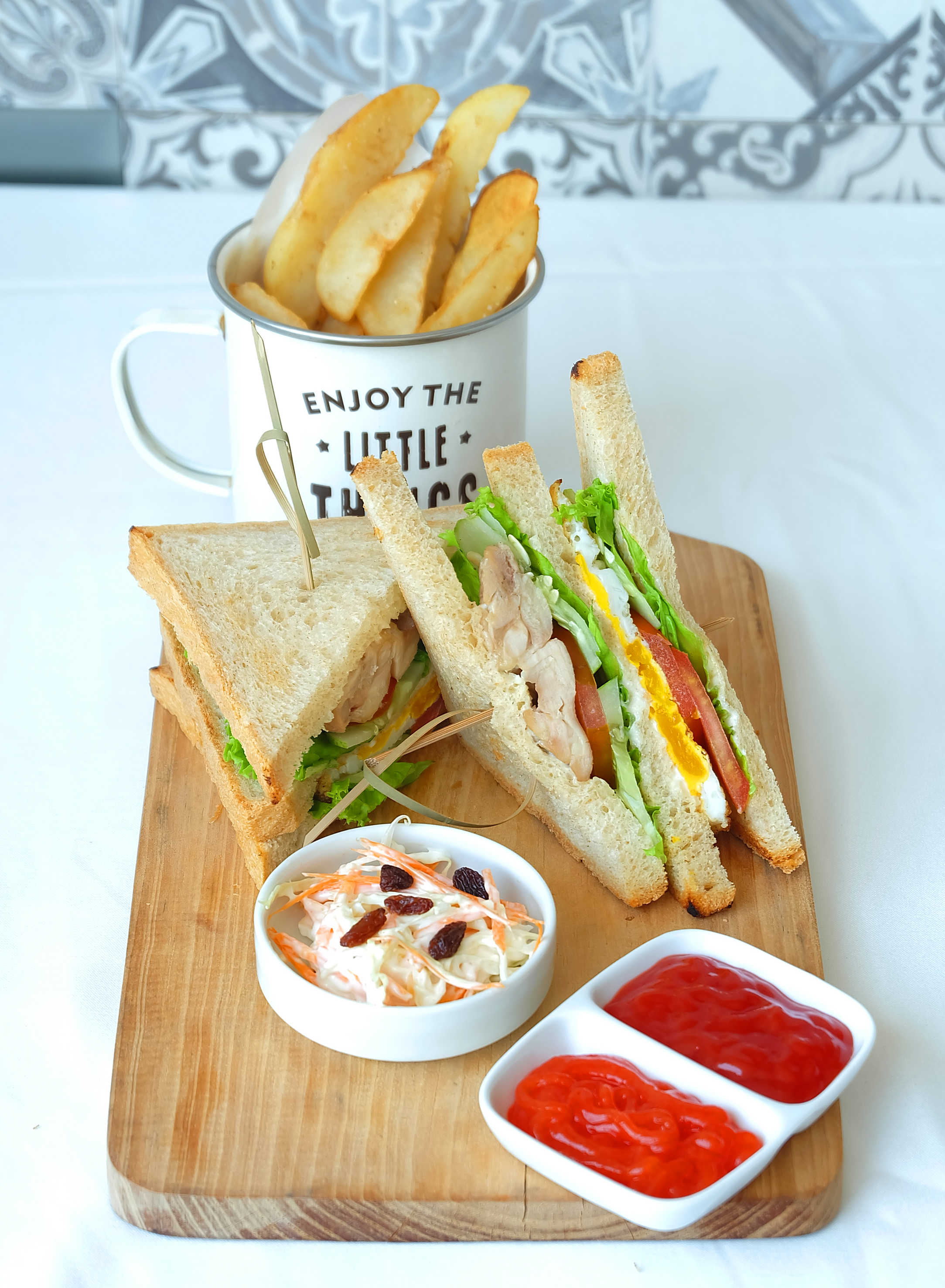 Classic club sandwich with chicken, egg, fries, coleslaw, and ketchup.