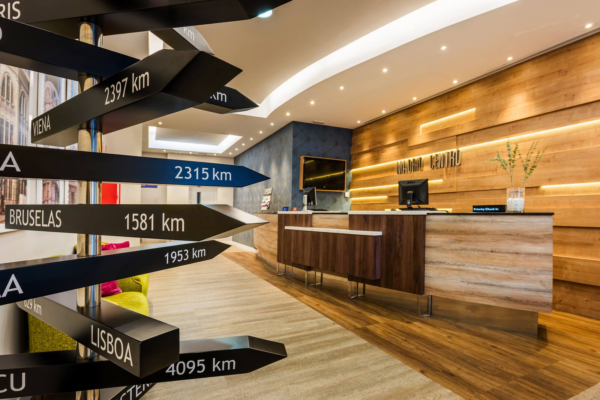 Hotel reception desk with "Madrid Centro" sign and multi-directional city signpost.