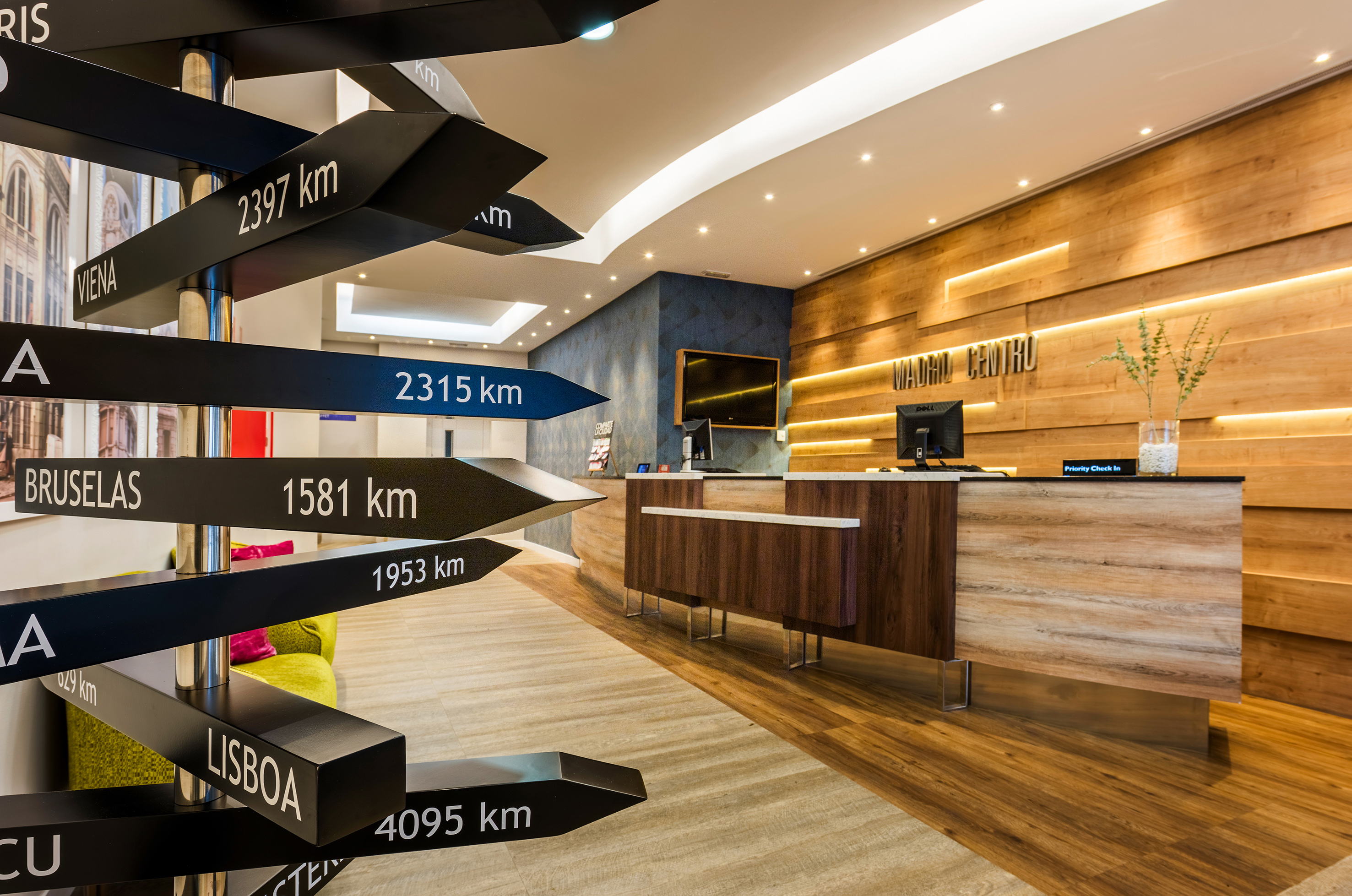 Hotel reception desk with "Madrid Centro" sign and multi-directional city signpost.
