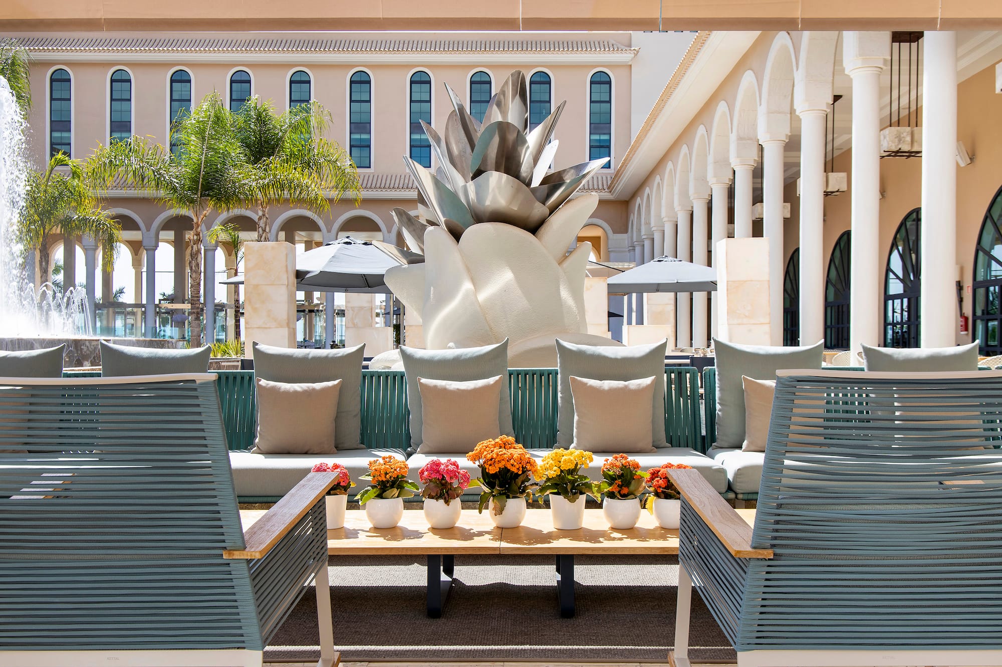 Luxury patio with modern seating, colorful flowers, and large agave sculpture.