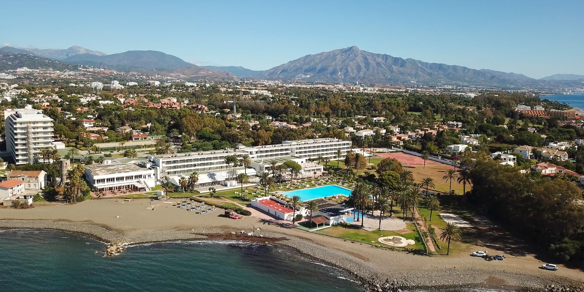 a beach with a swimming pool and a large building