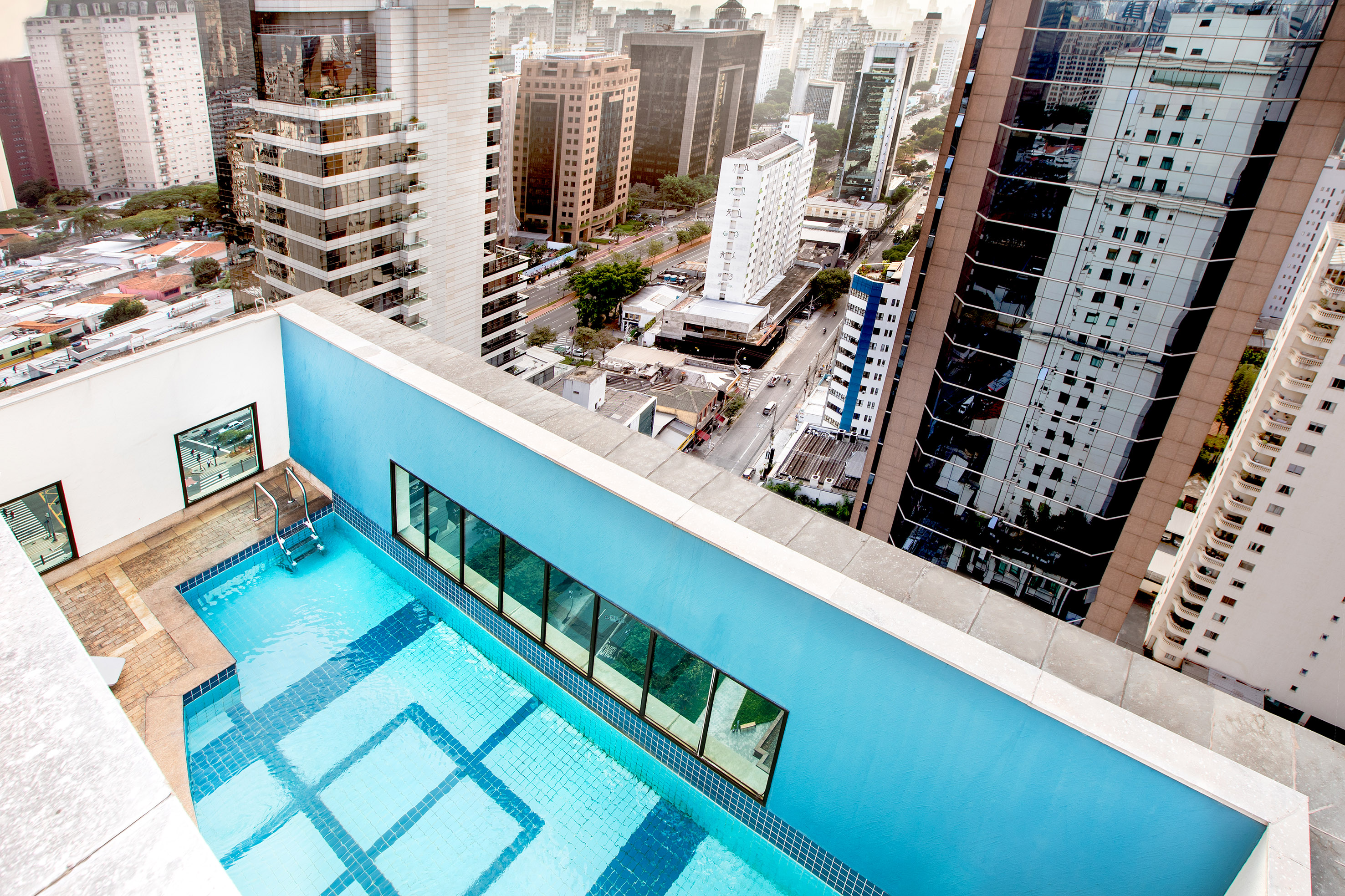 Rooftop swimming pool overlooking a bustling city with tall buildings.