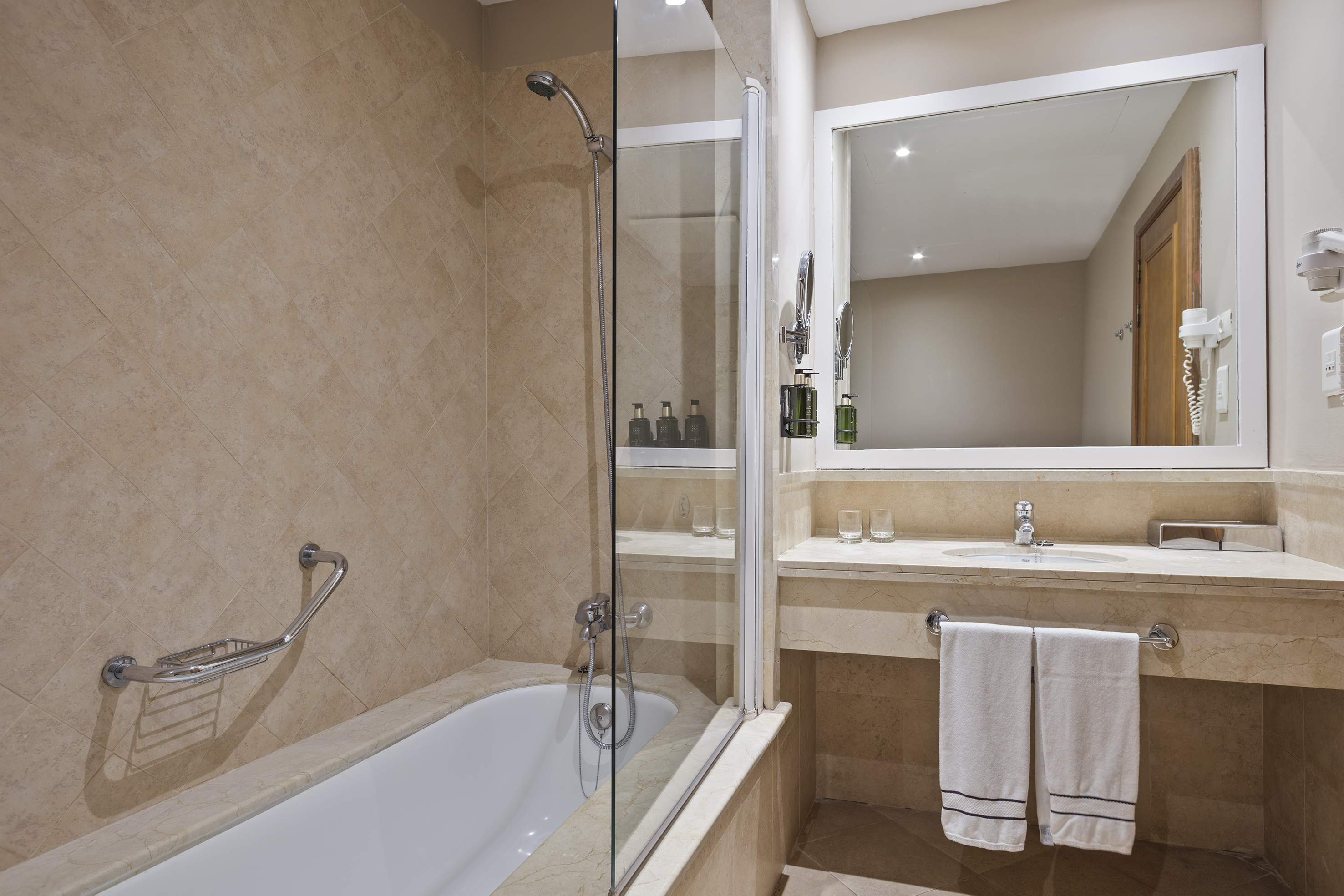 Contemporary tiled bathroom with bathtub, shower, vanity, and mirror.