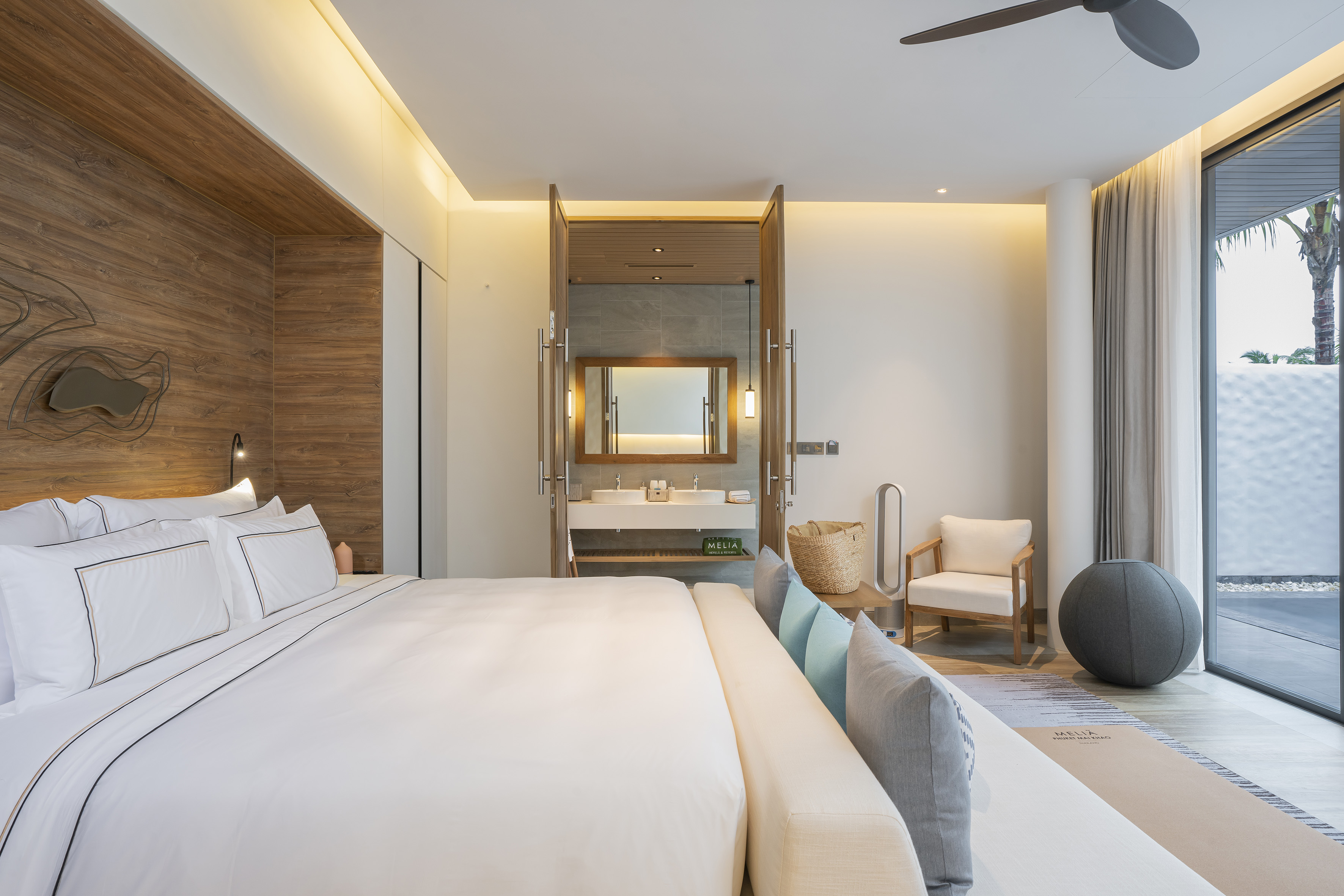Contemporary bedroom with king bed, open bathroom, and natural light.