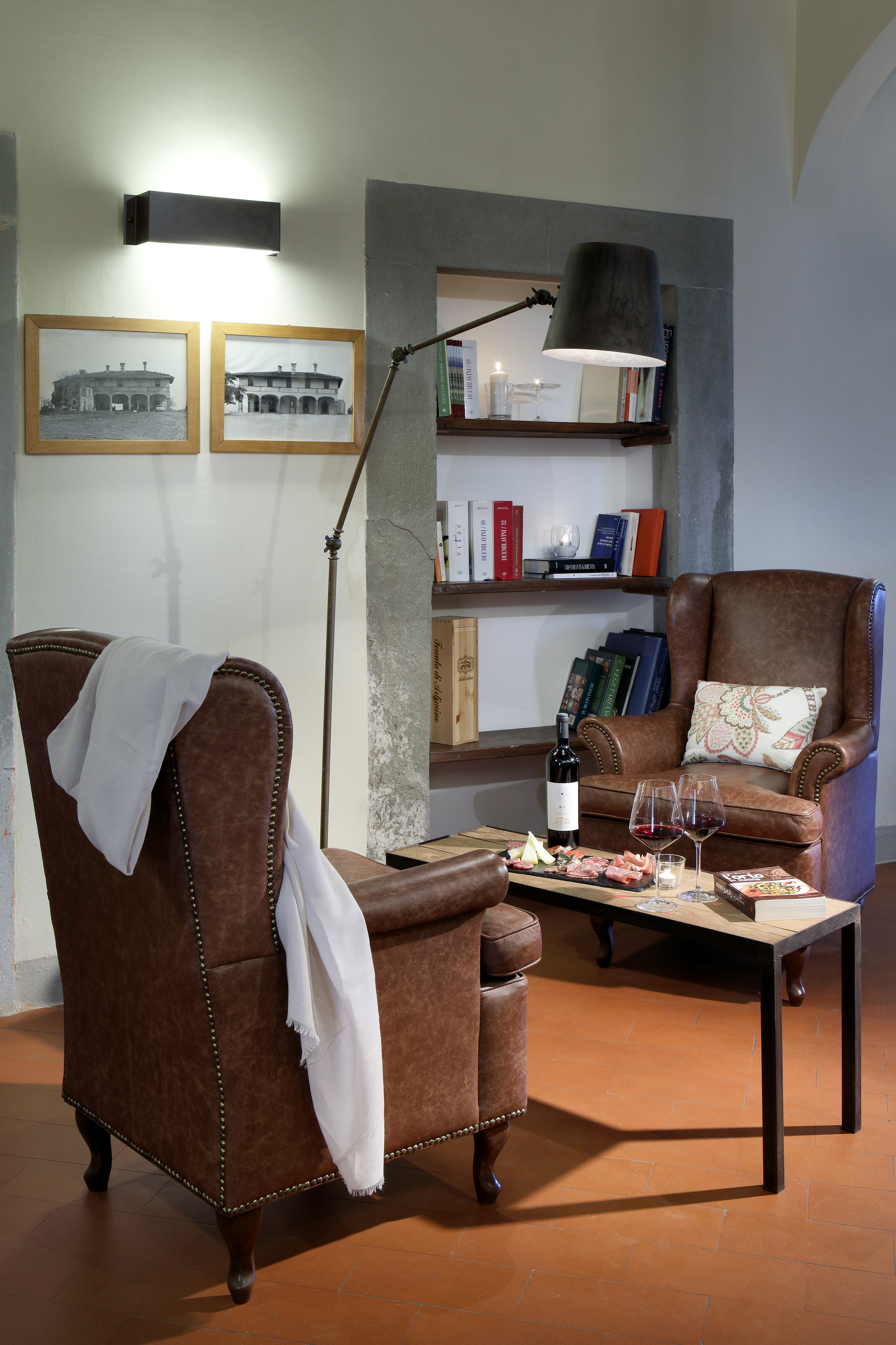 Brown leather armchairs, wine & snacks in a rustic living room with books.