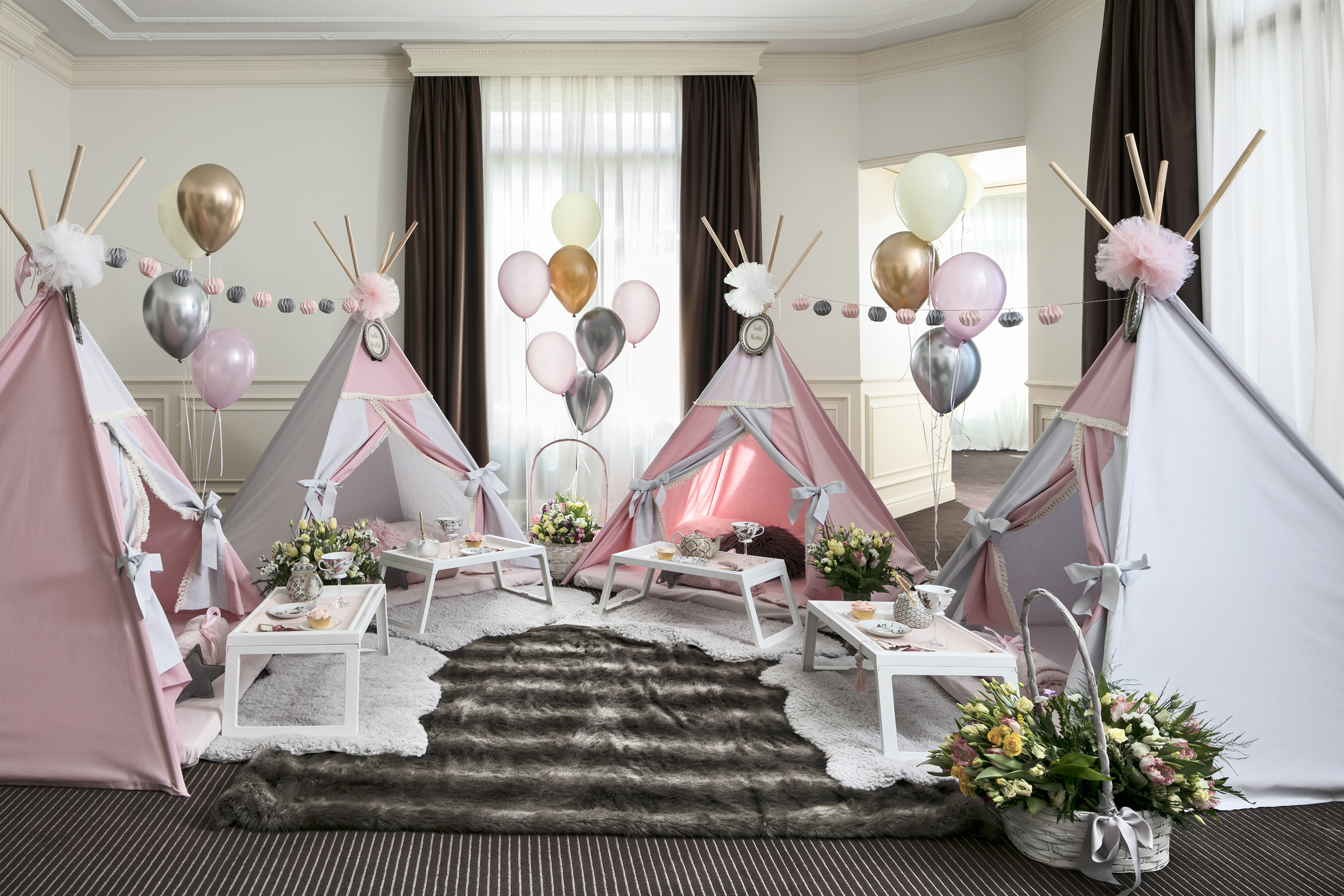 Pink and grey teepee sleepover party setup with balloons, tea sets, and flowers.
