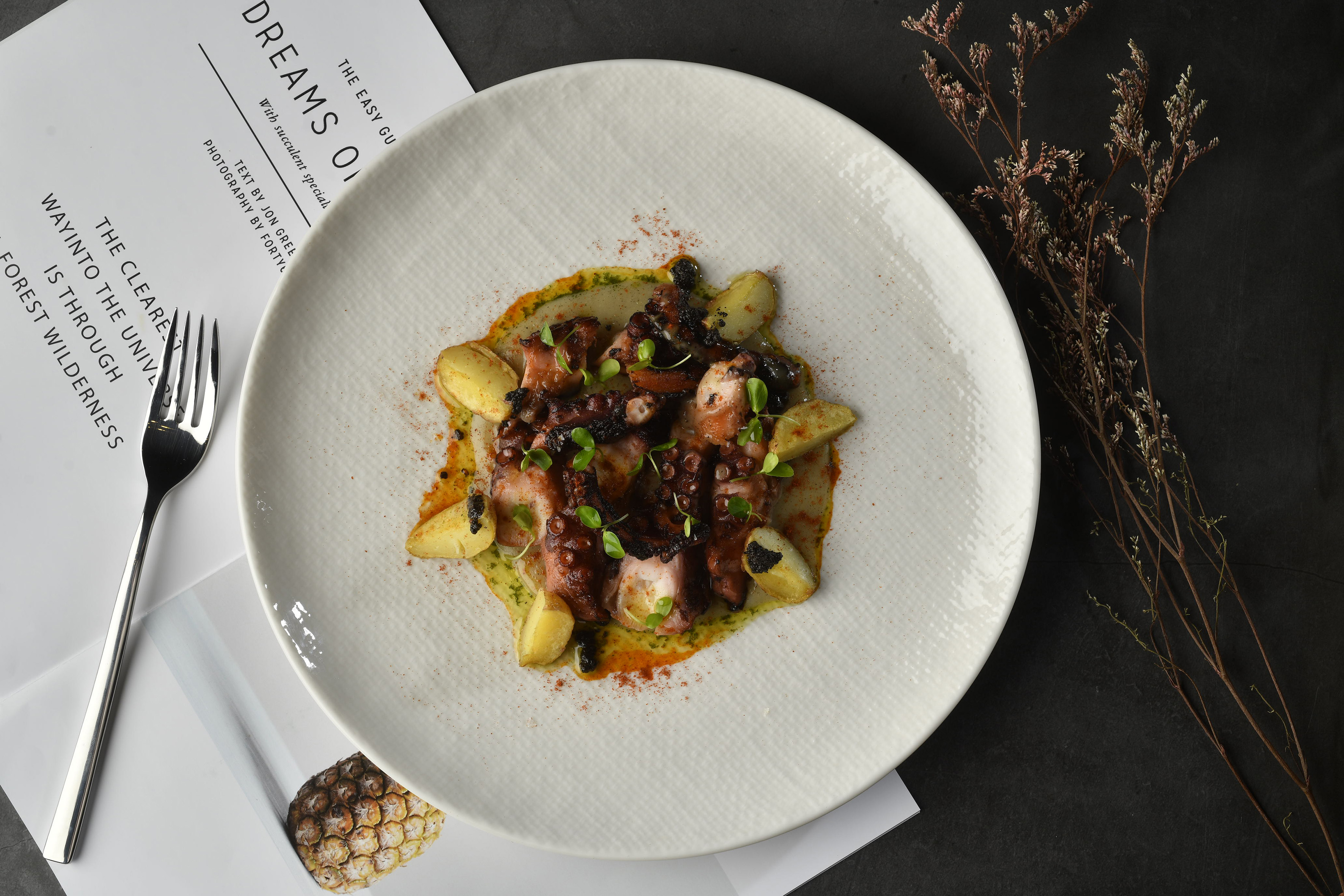 Grilled octopus with potatoes and green sauce on a white plate, gourmet seafood.
