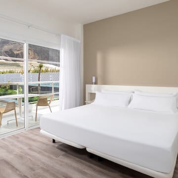 a bed with white sheets and a glass door