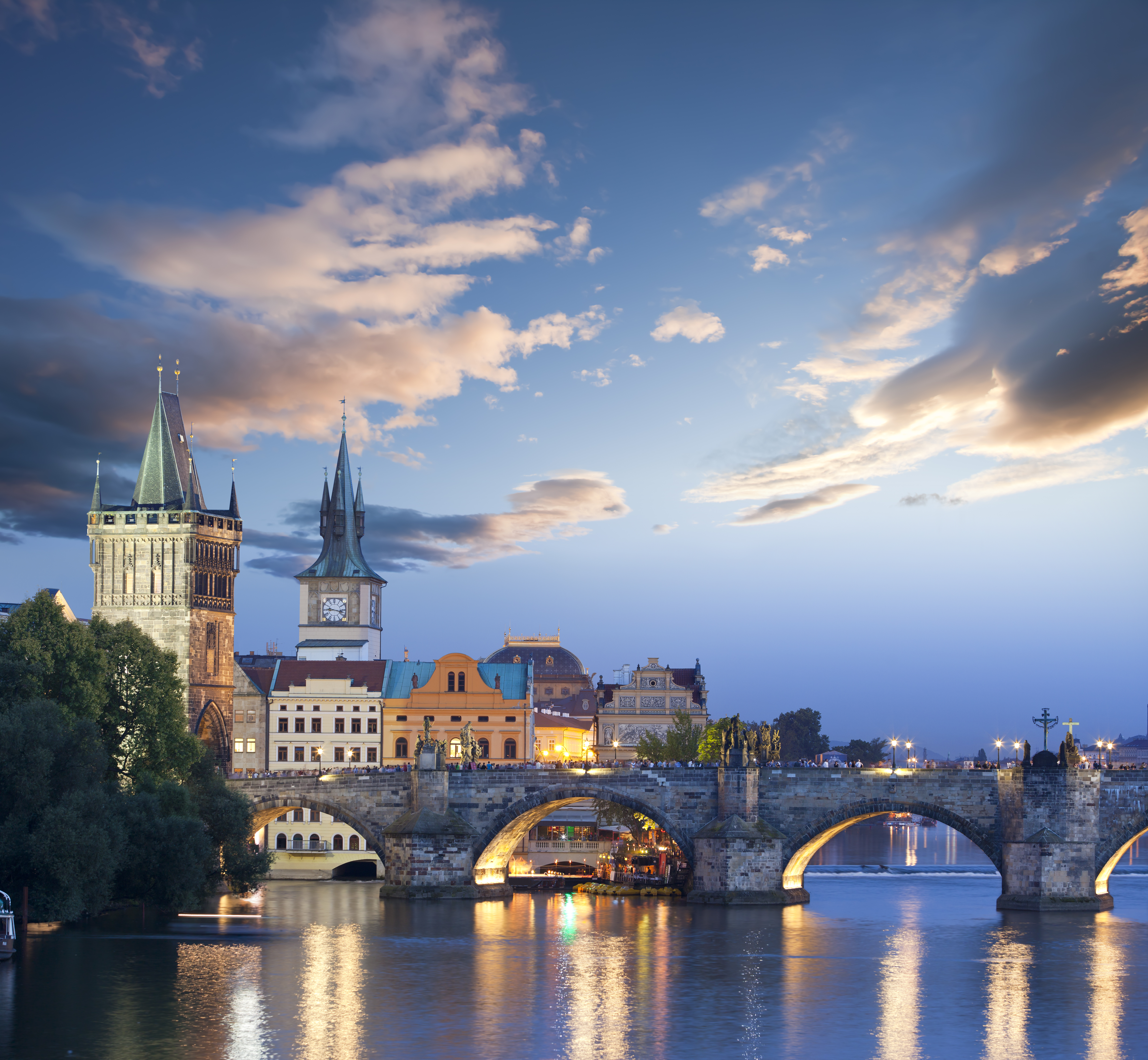 Historic Charles Bridge over Vltava River with Prague Old Town towers at twilight.