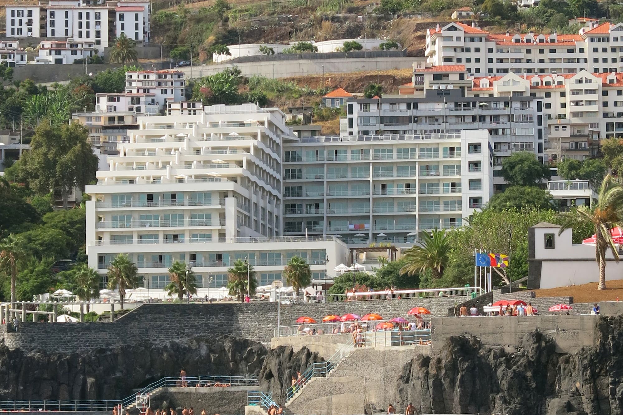 a group of people on a rocky hill next to a body of water