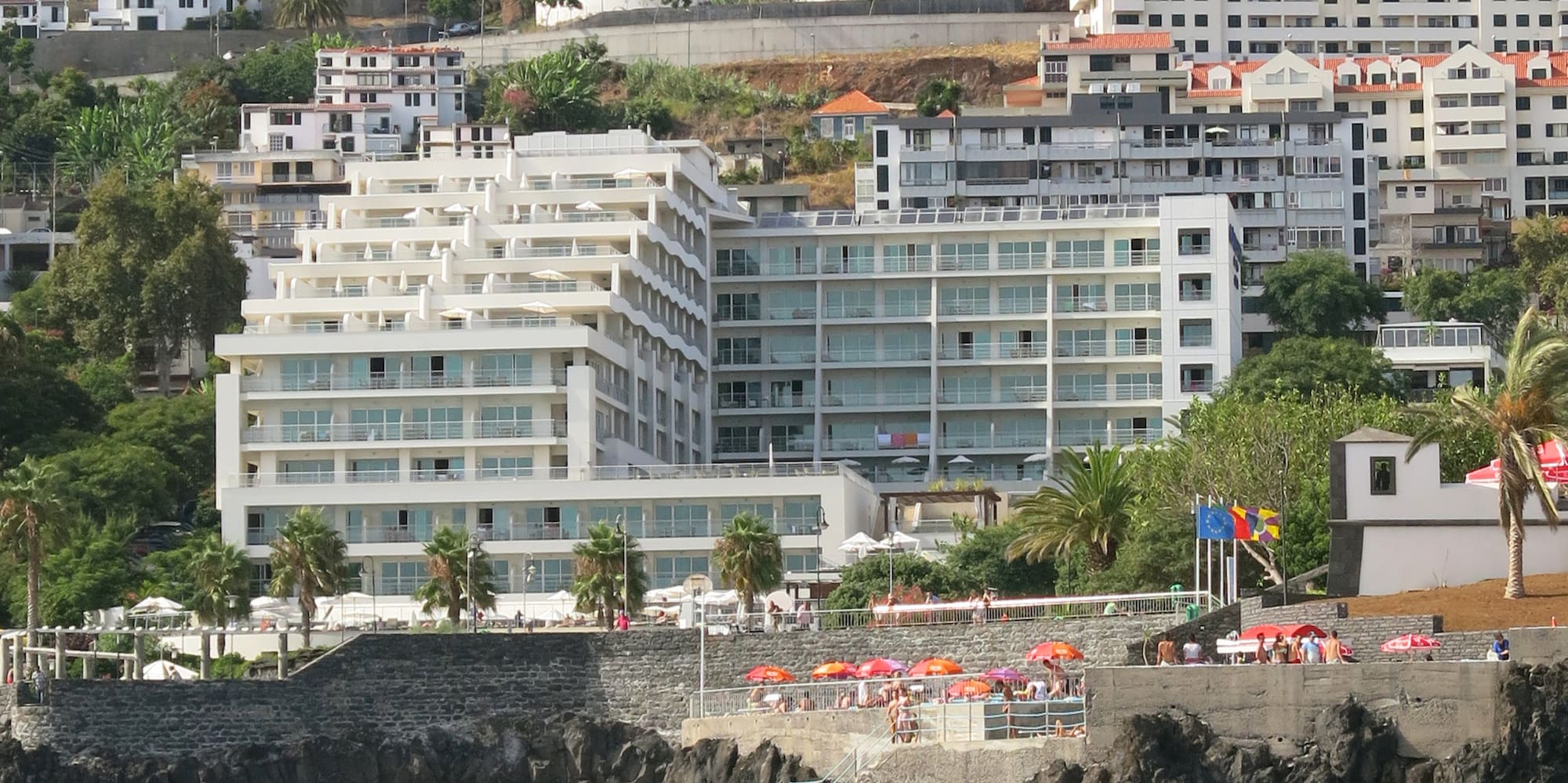 a group of people on a rocky hill next to a body of water