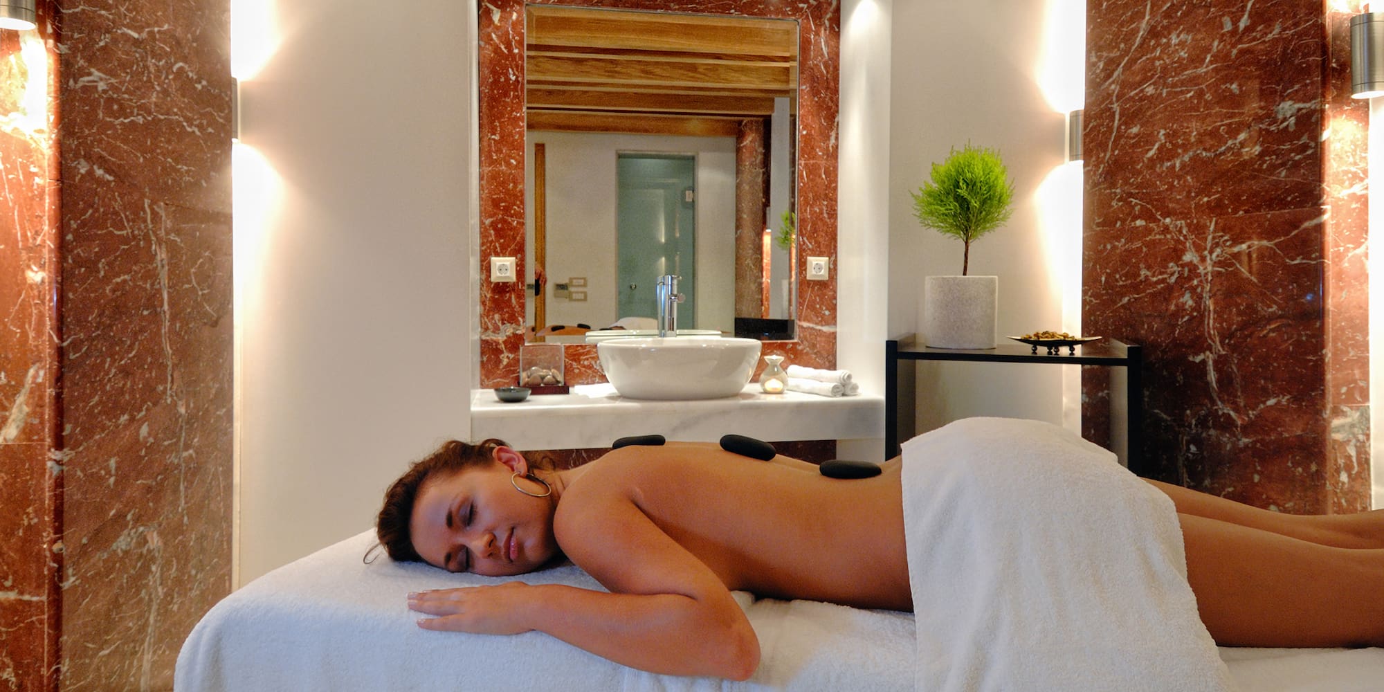 a woman lying on a massage table with hot stones on her back