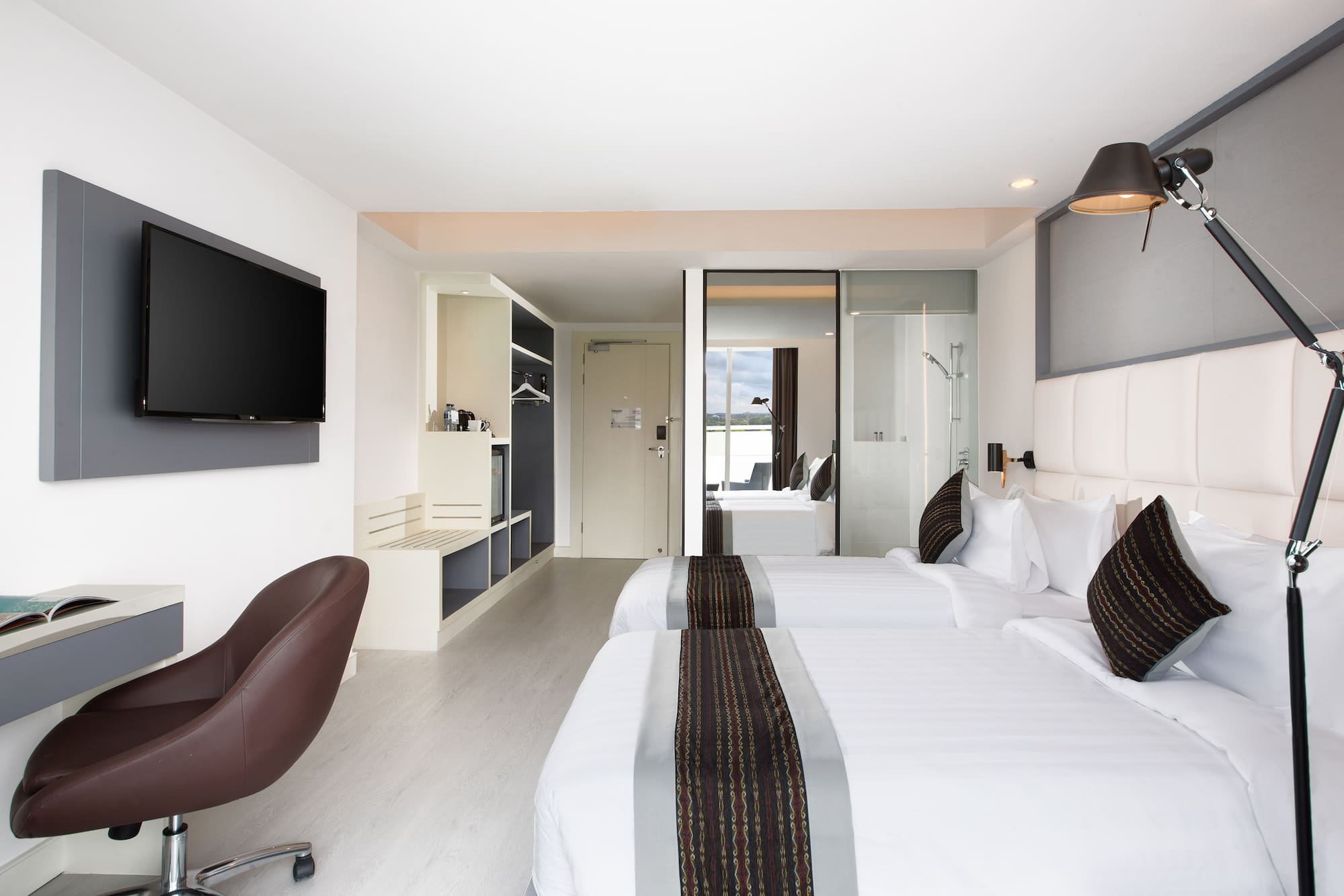 a room with white beds and a brown chair