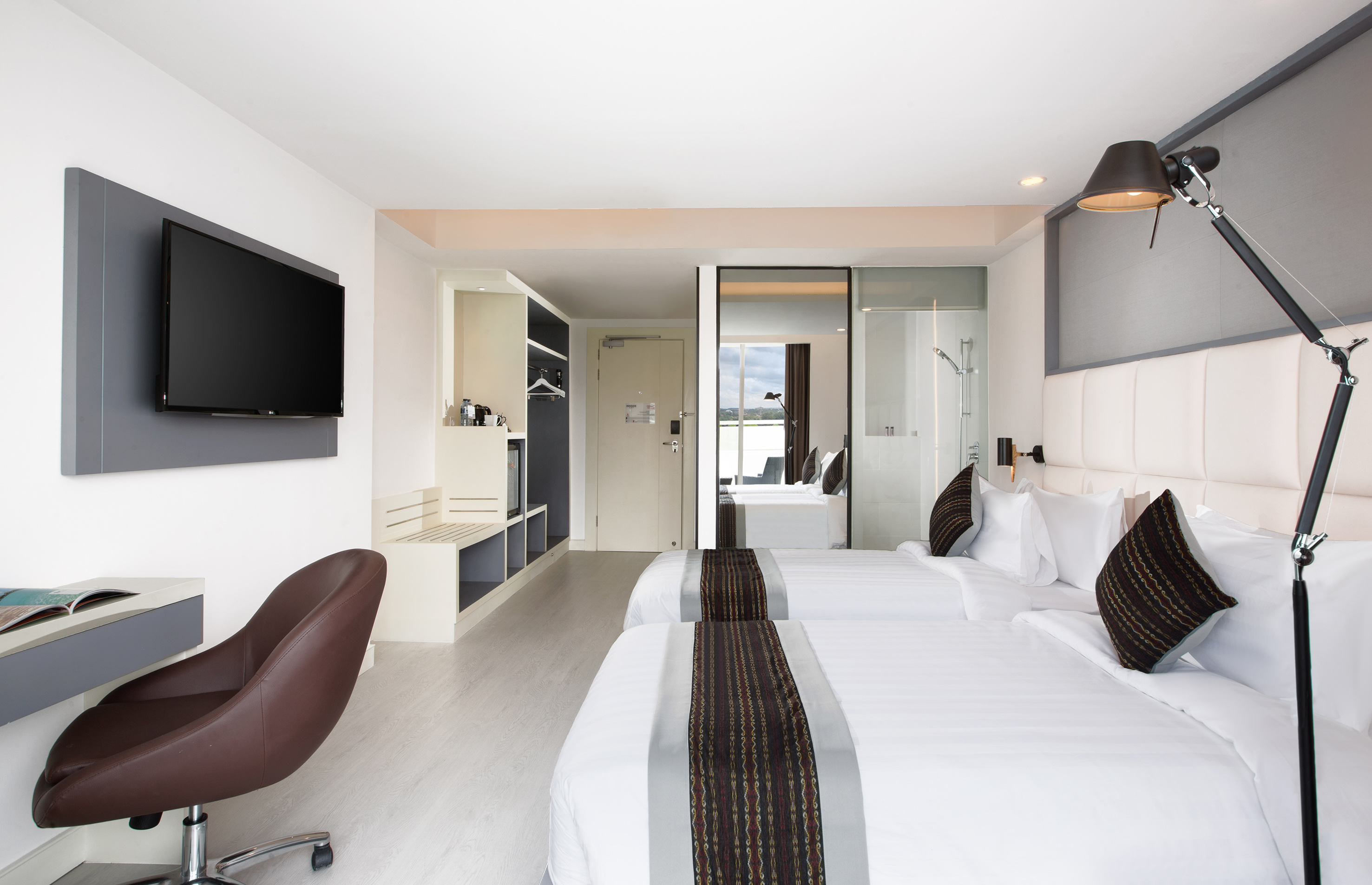 a room with white beds and a brown chair