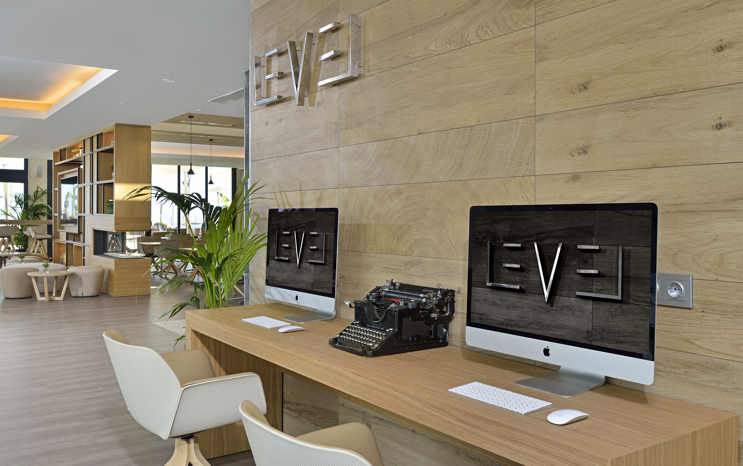 Modern lobby with "LEVEL" sign, computers, and vintage typewriter.