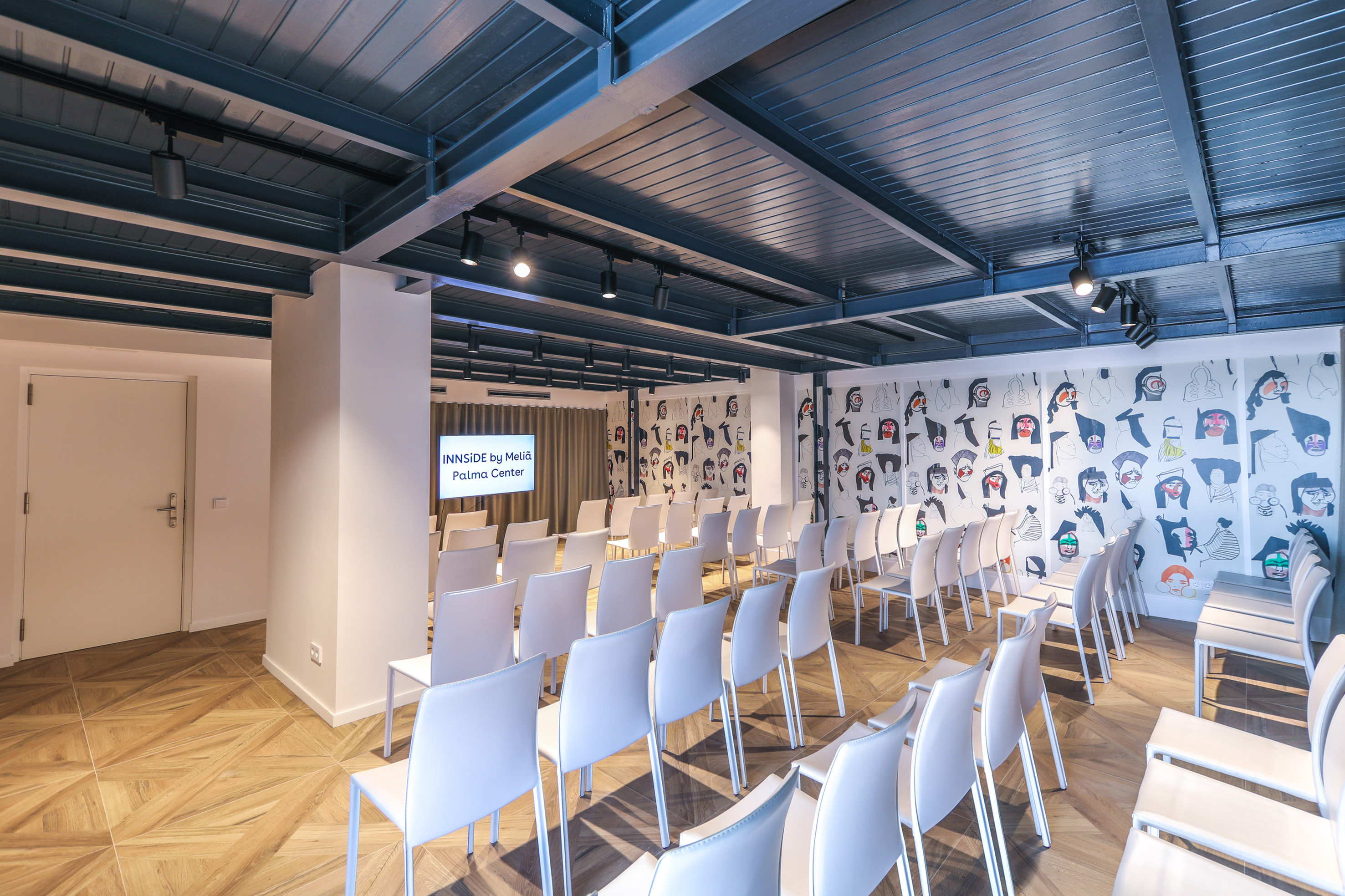 INNSiDE by Meliá meeting room: white chairs, artistic walls, presentation screen.