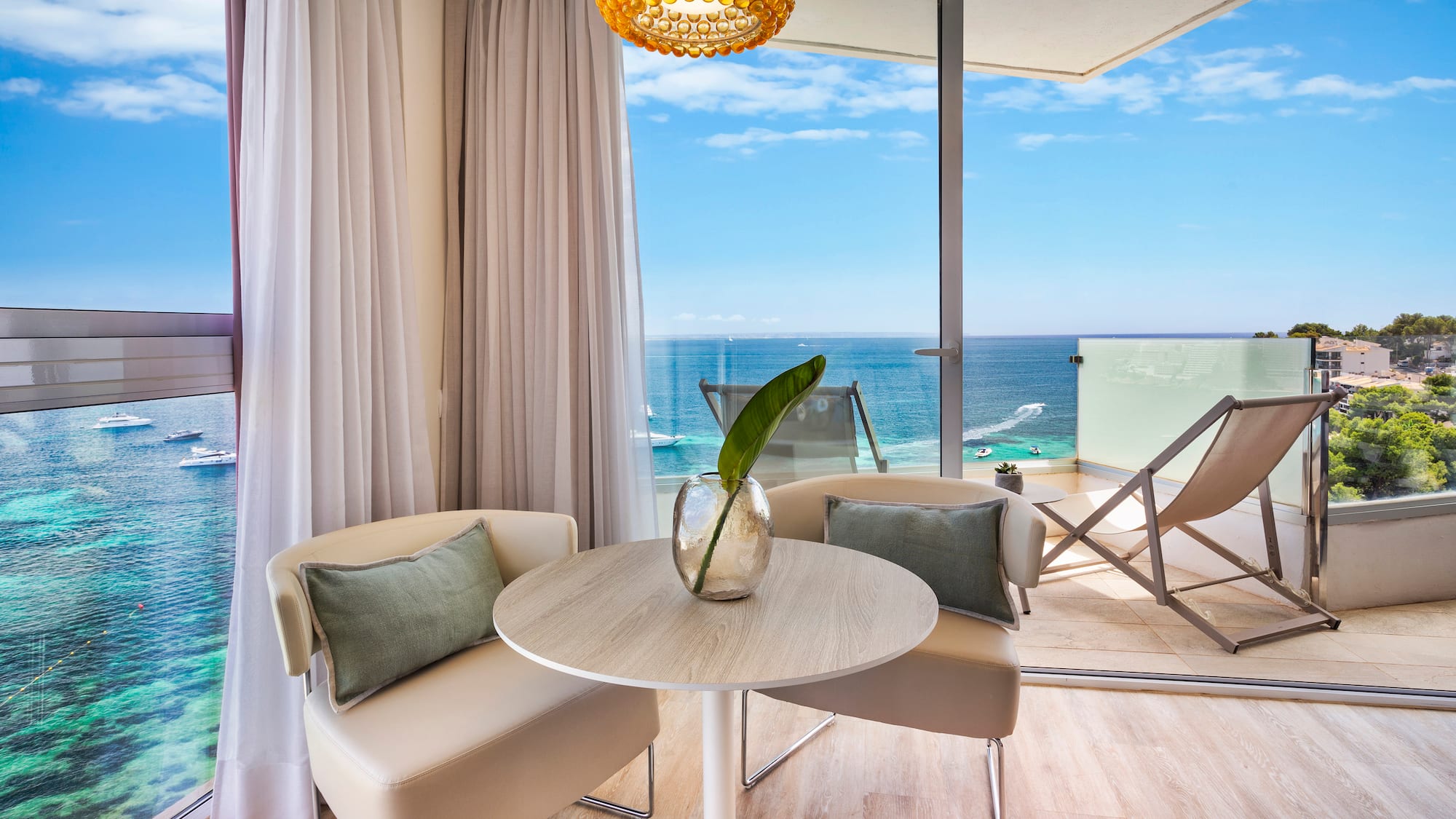 a room with a table and chairs and a view of the ocean