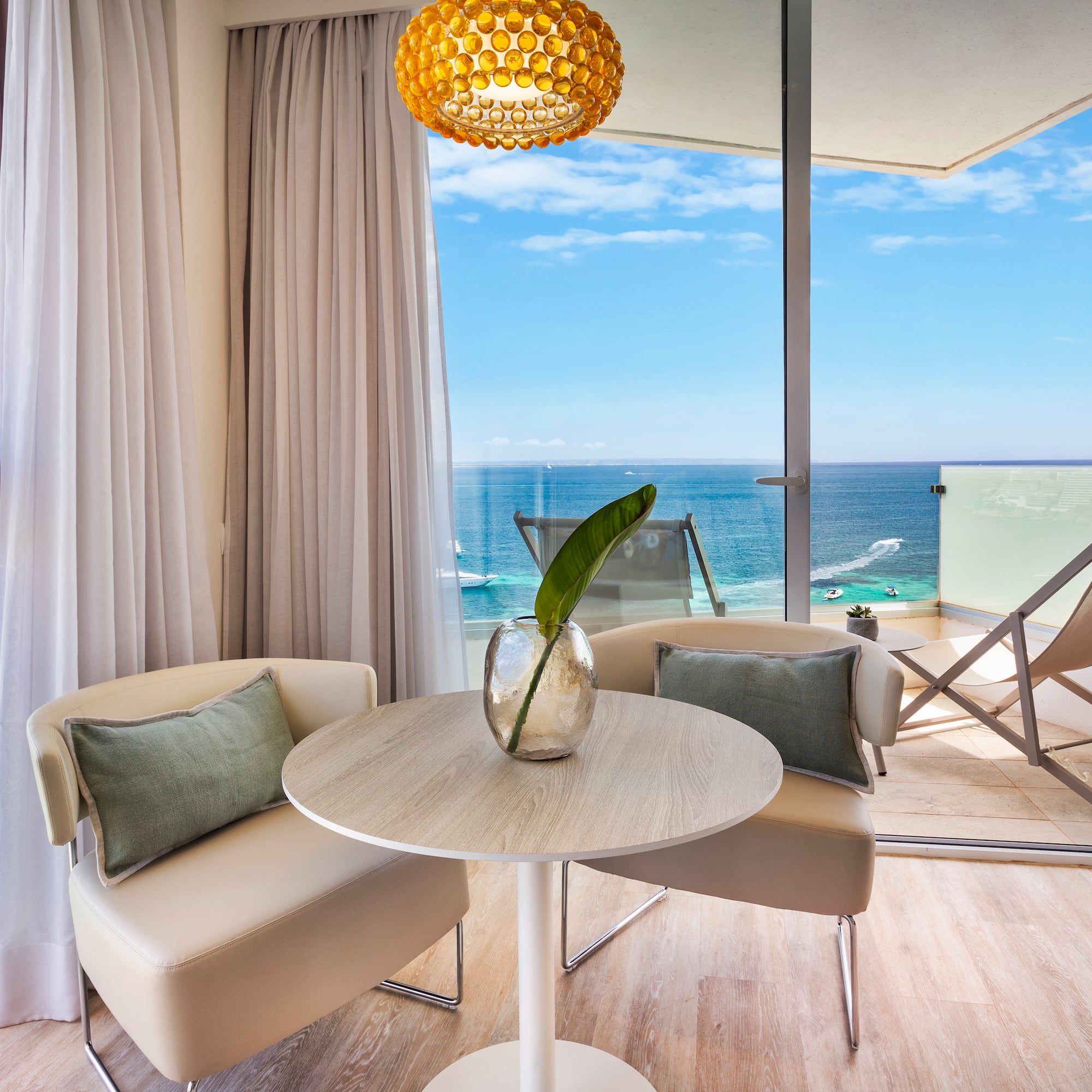 a room with a table and chairs and a view of the ocean