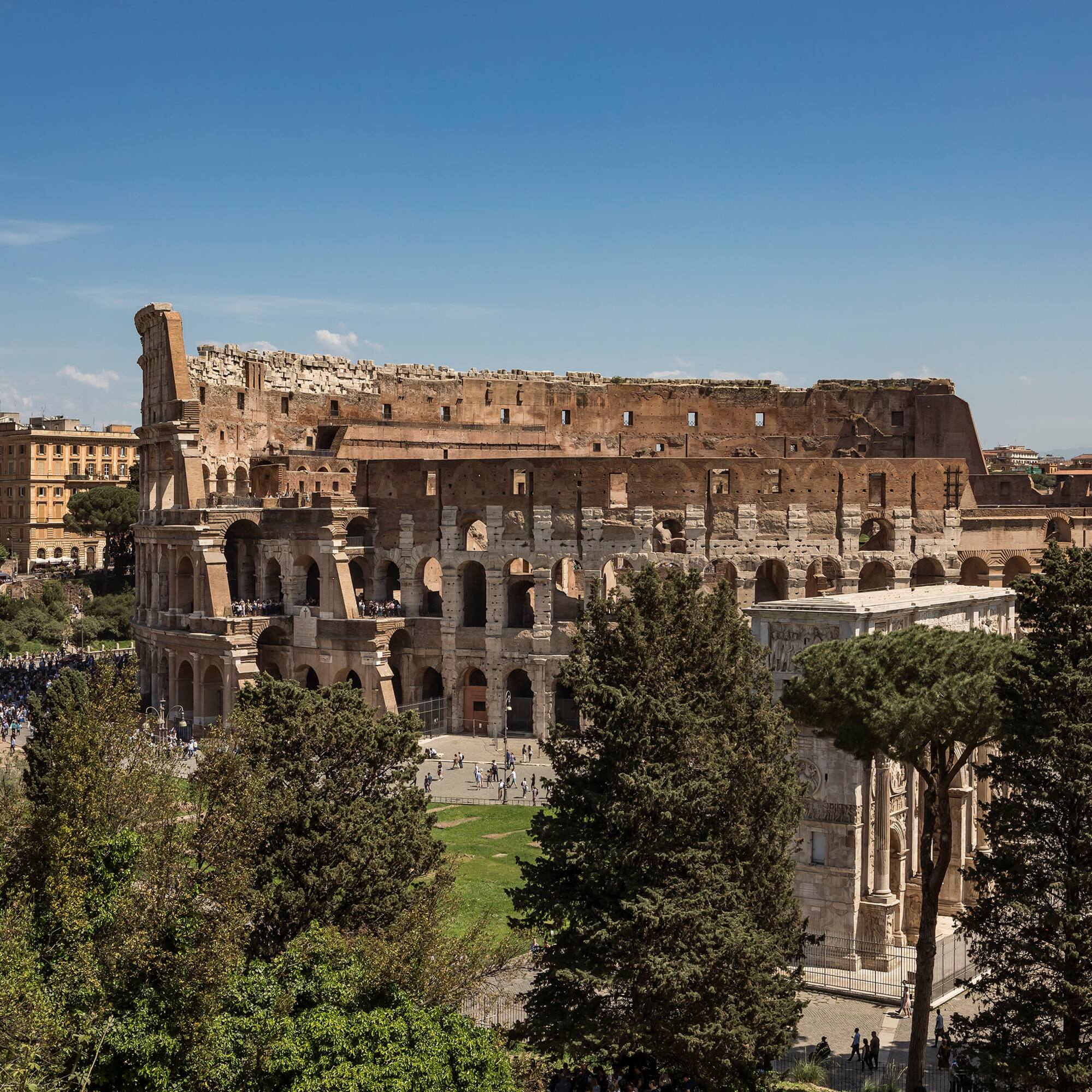 a large stone building with trees and people in the background