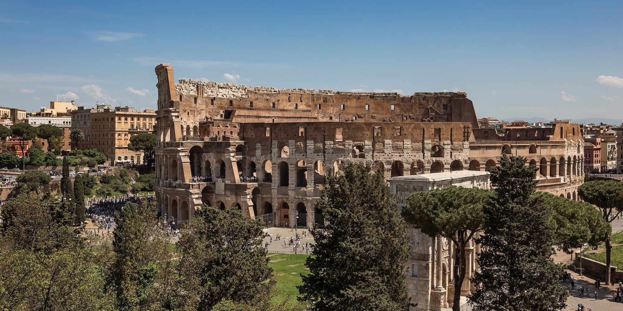 a large stone building with trees and people in the background