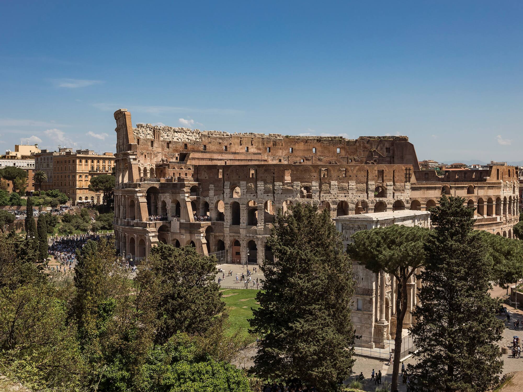 a large stone building with trees and people in the background