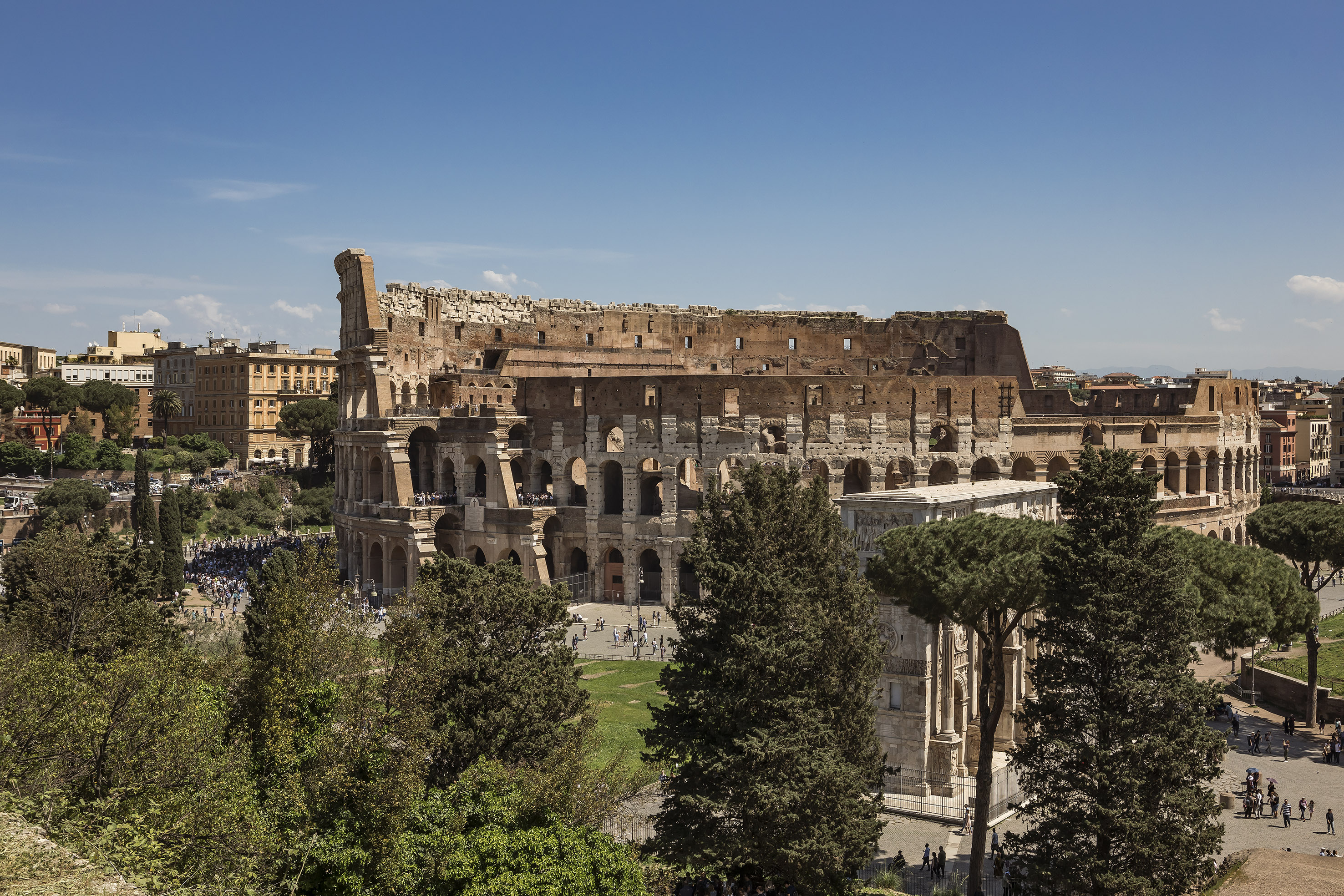 Colosseum in Rome, Italy, with Arch of Constantine and surrounding trees.