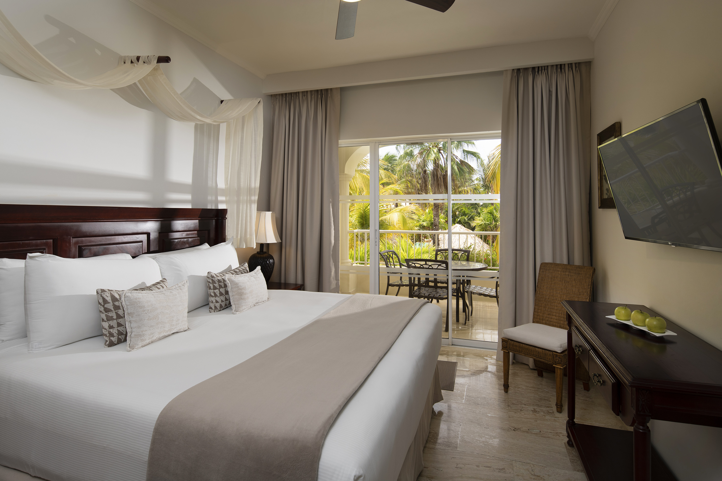 Spacious hotel room with king bed, private balcony, and tropical garden view.