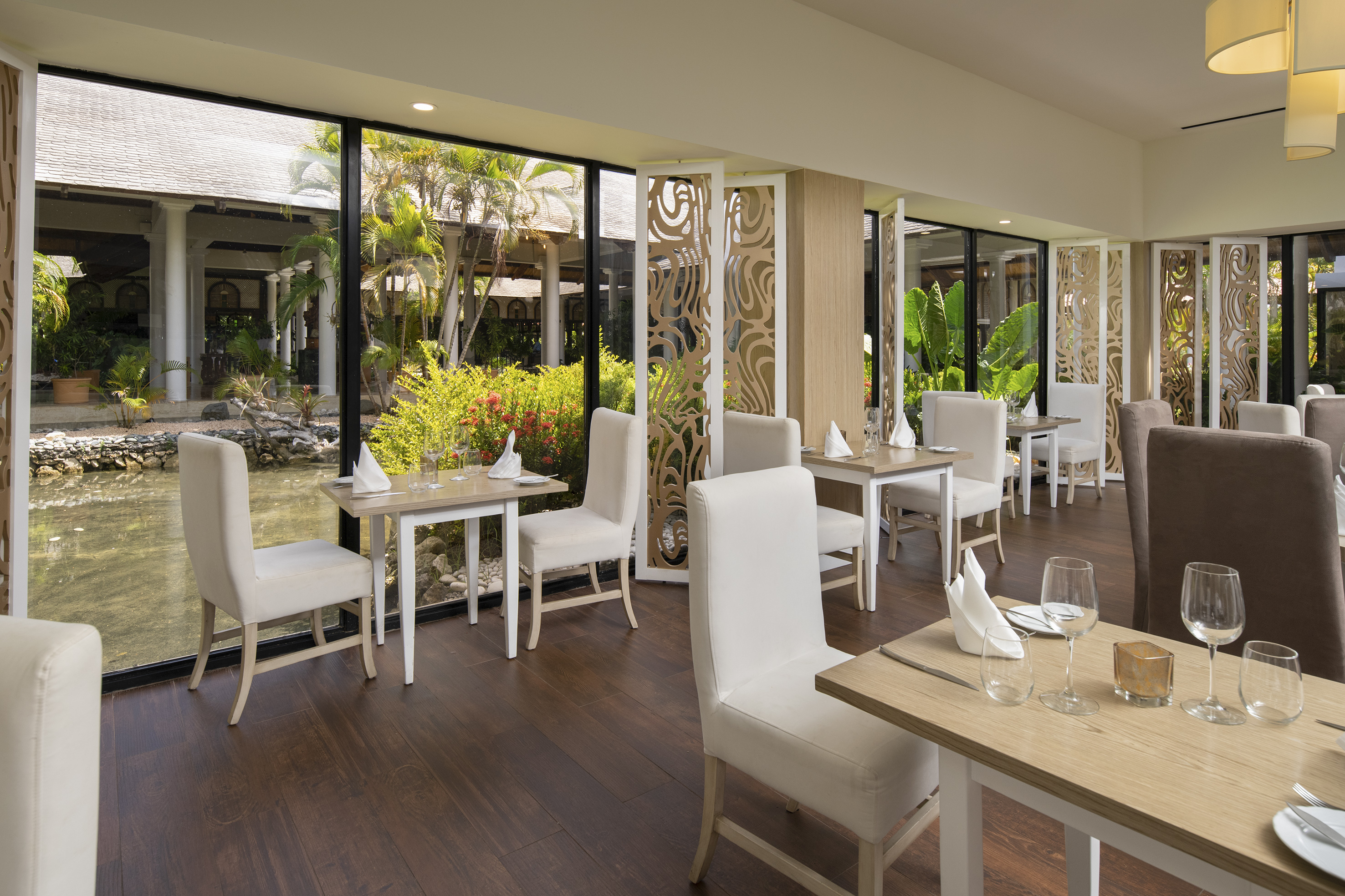 Elegant restaurant dining room with tropical garden and pond views.