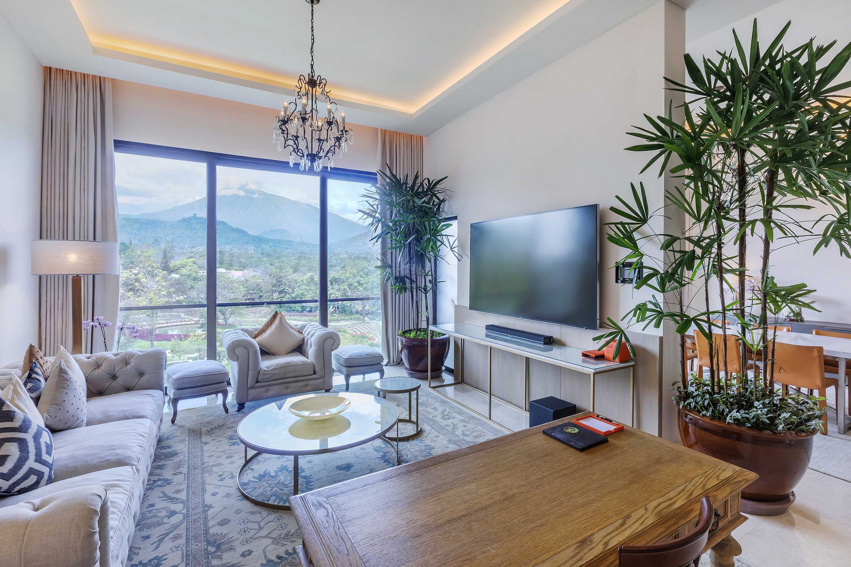 Modern luxury living room with mountain view, large windows, elegant decor.