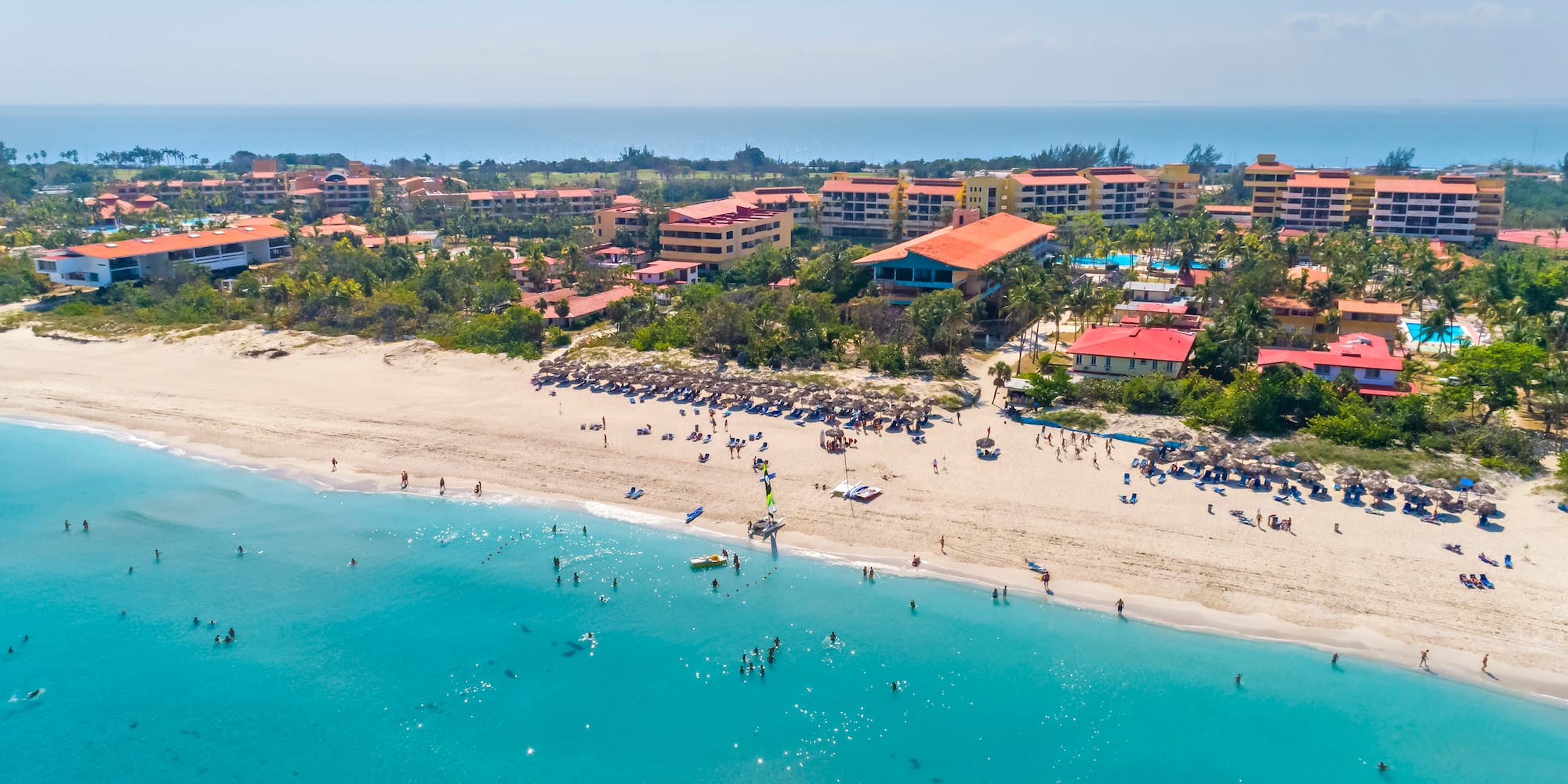 a beach with buildings and blue water