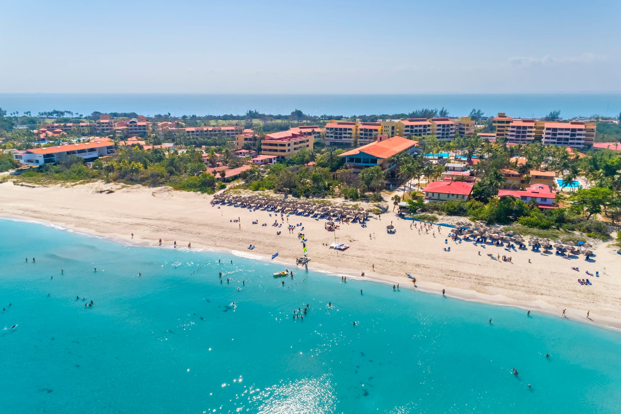 a beach with buildings and blue water