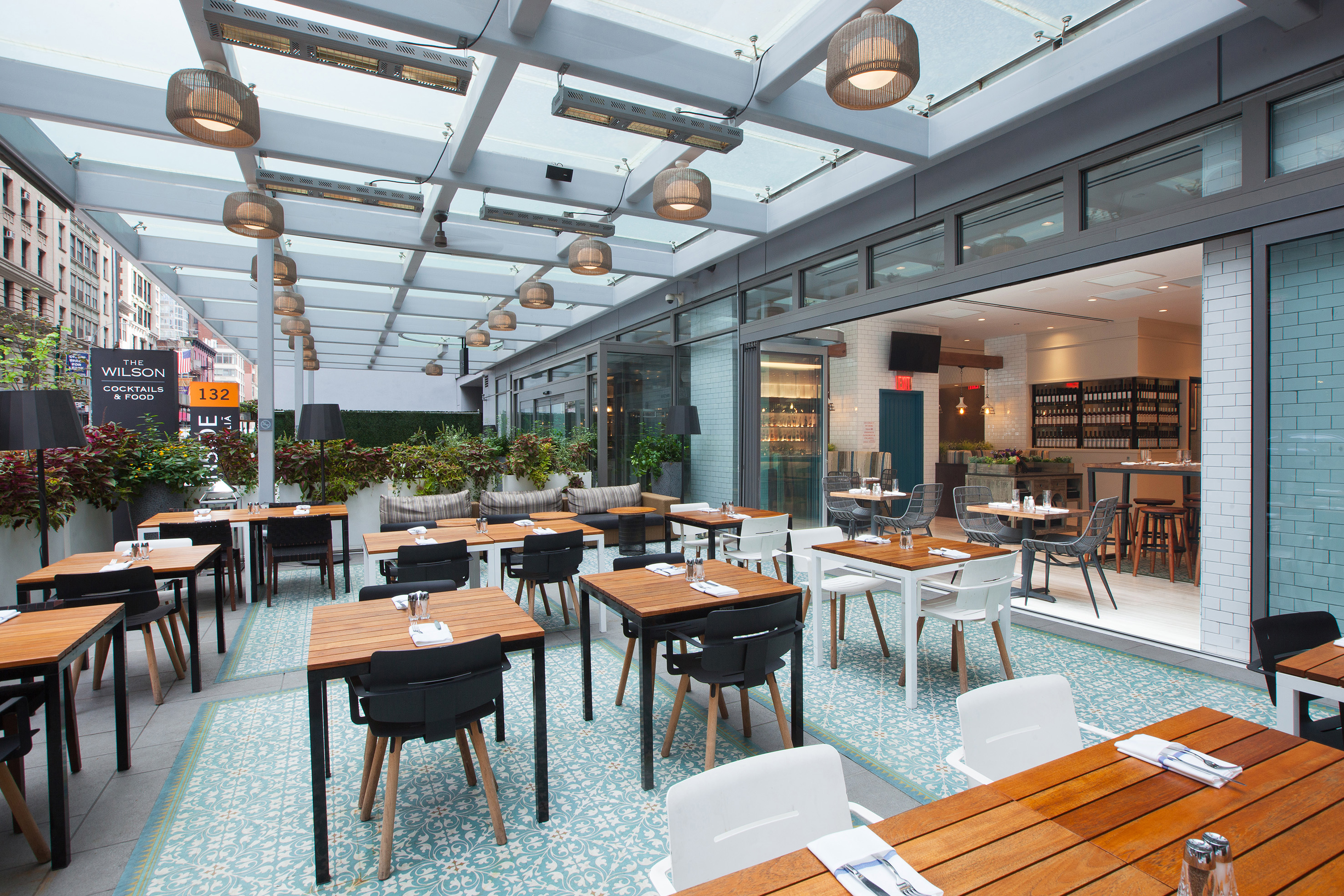 The Wilson outdoor patio: modern dining tables, patterned floor, glass roof.
