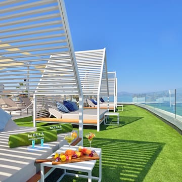 a deck with lounge chairs and a table on a green lawn